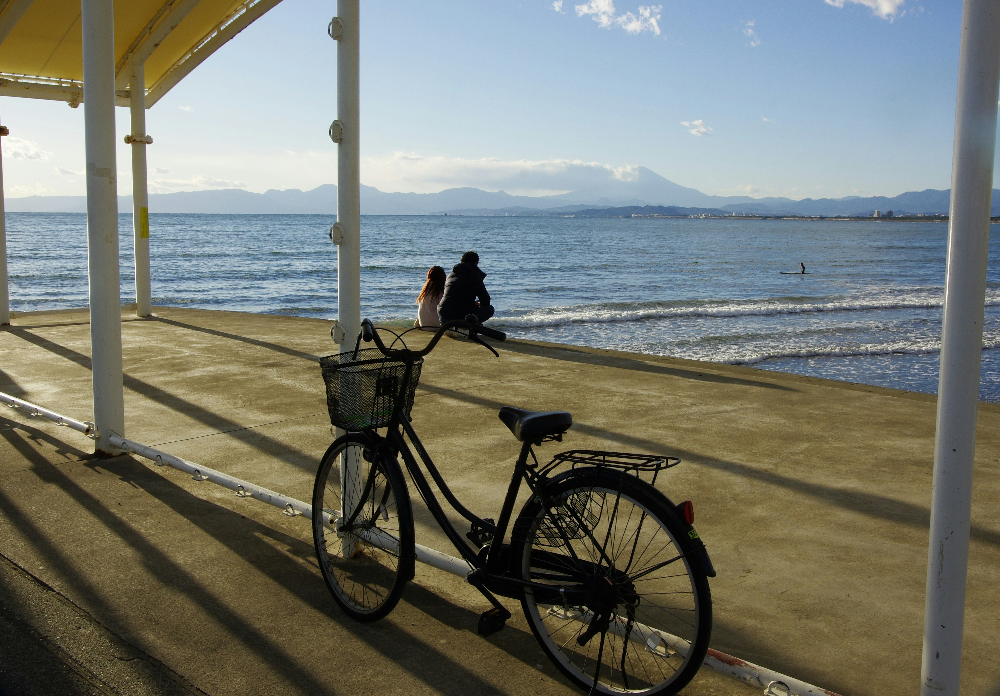 Vélo au bord de la mer avec une personne assise à proximité