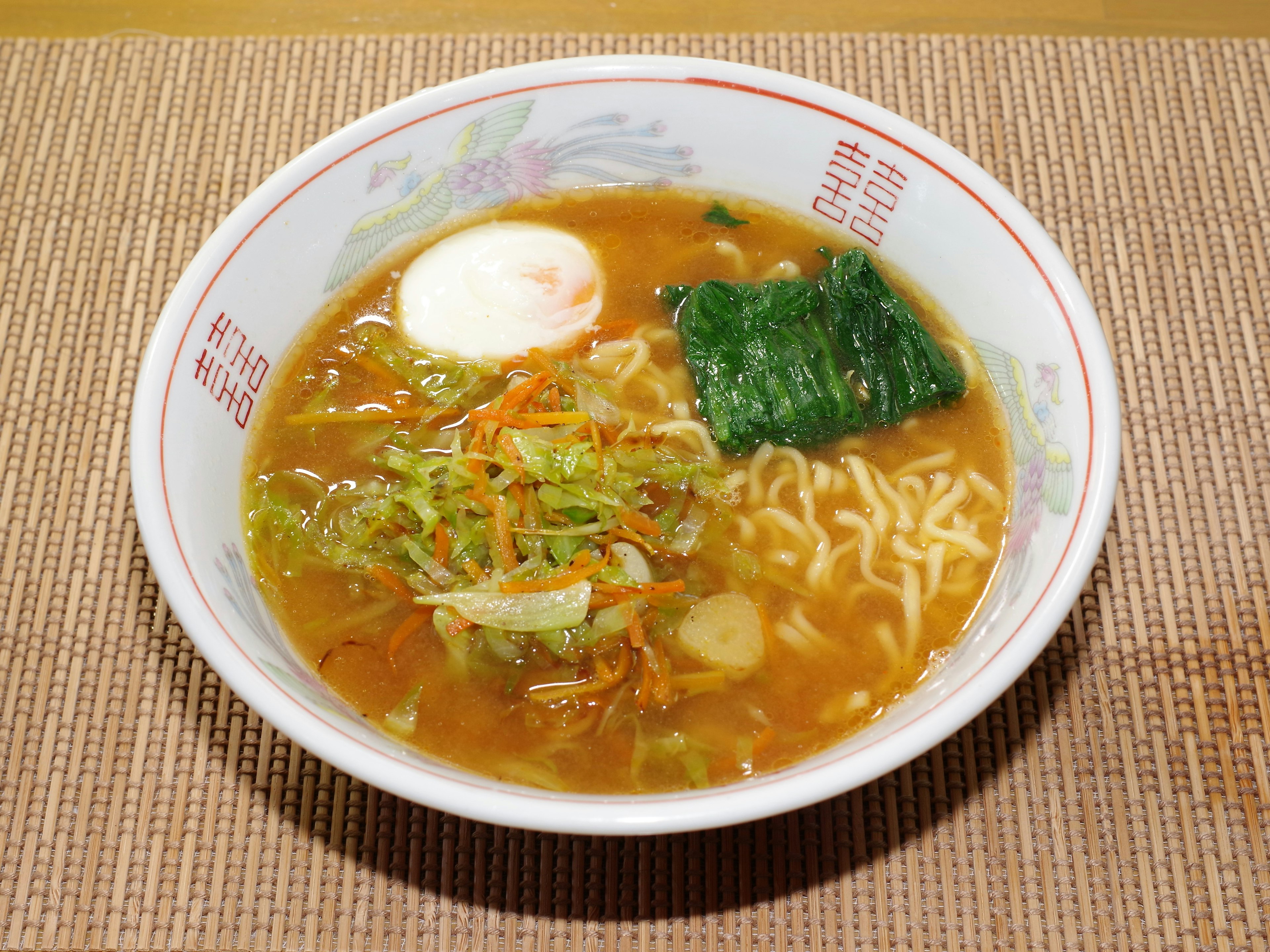 Bowl of ramen topped with soft boiled egg, nori, and vegetables