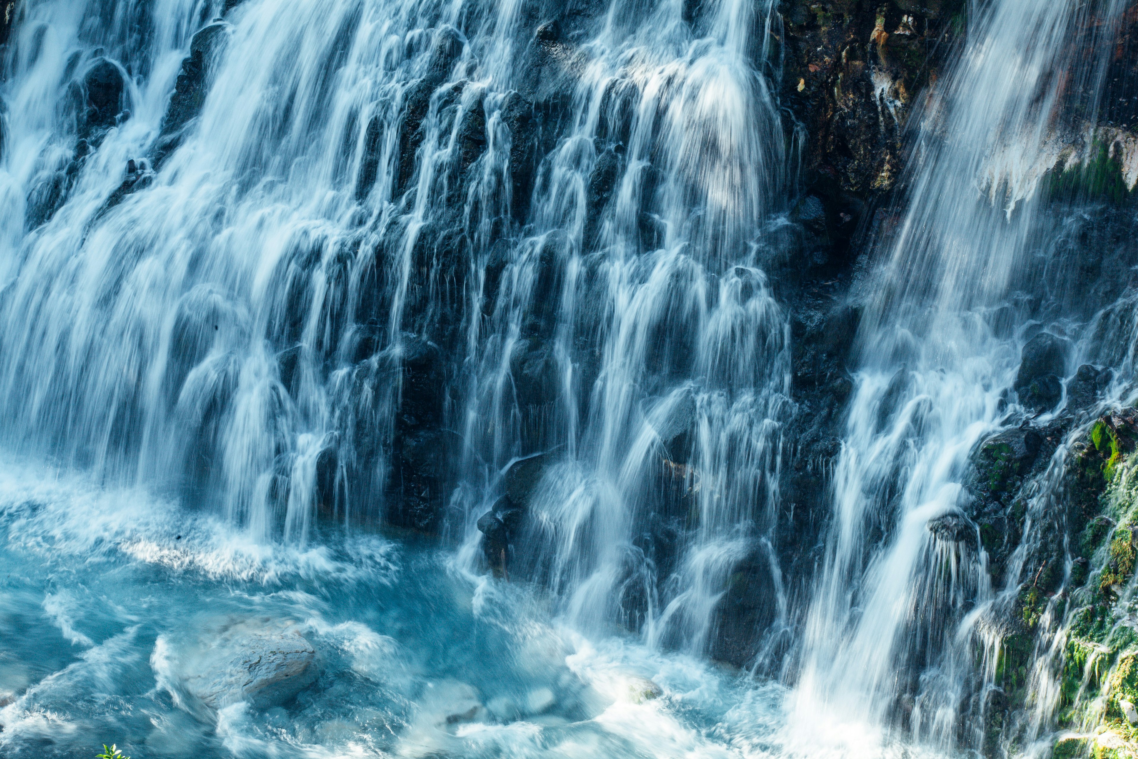 Hermosa cascada que fluye sobre rocas con agua azul clara