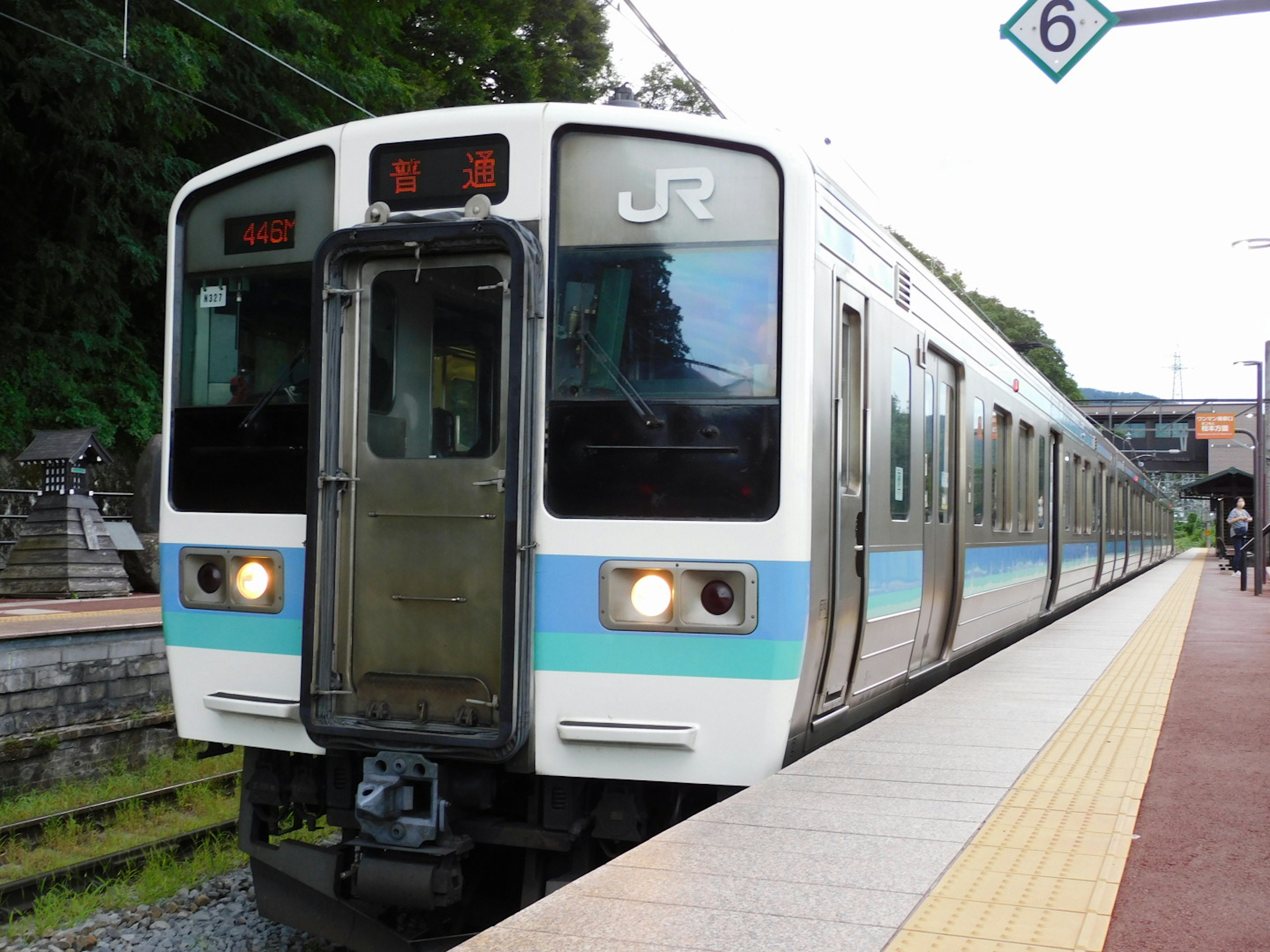 Train JR avec des rayures bleues arrêté à une station