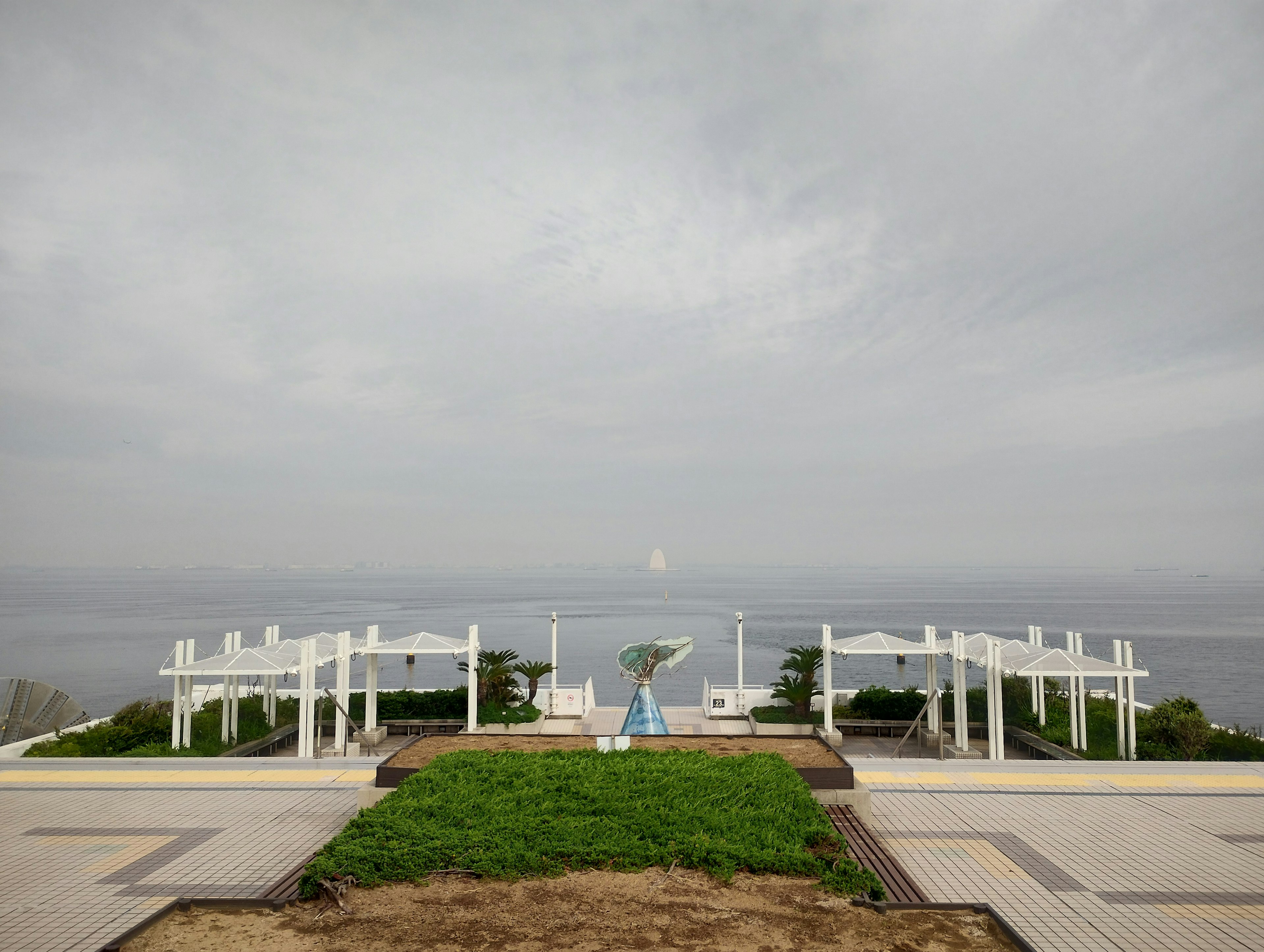 Pergola putih menghadap laut dengan rumput hijau