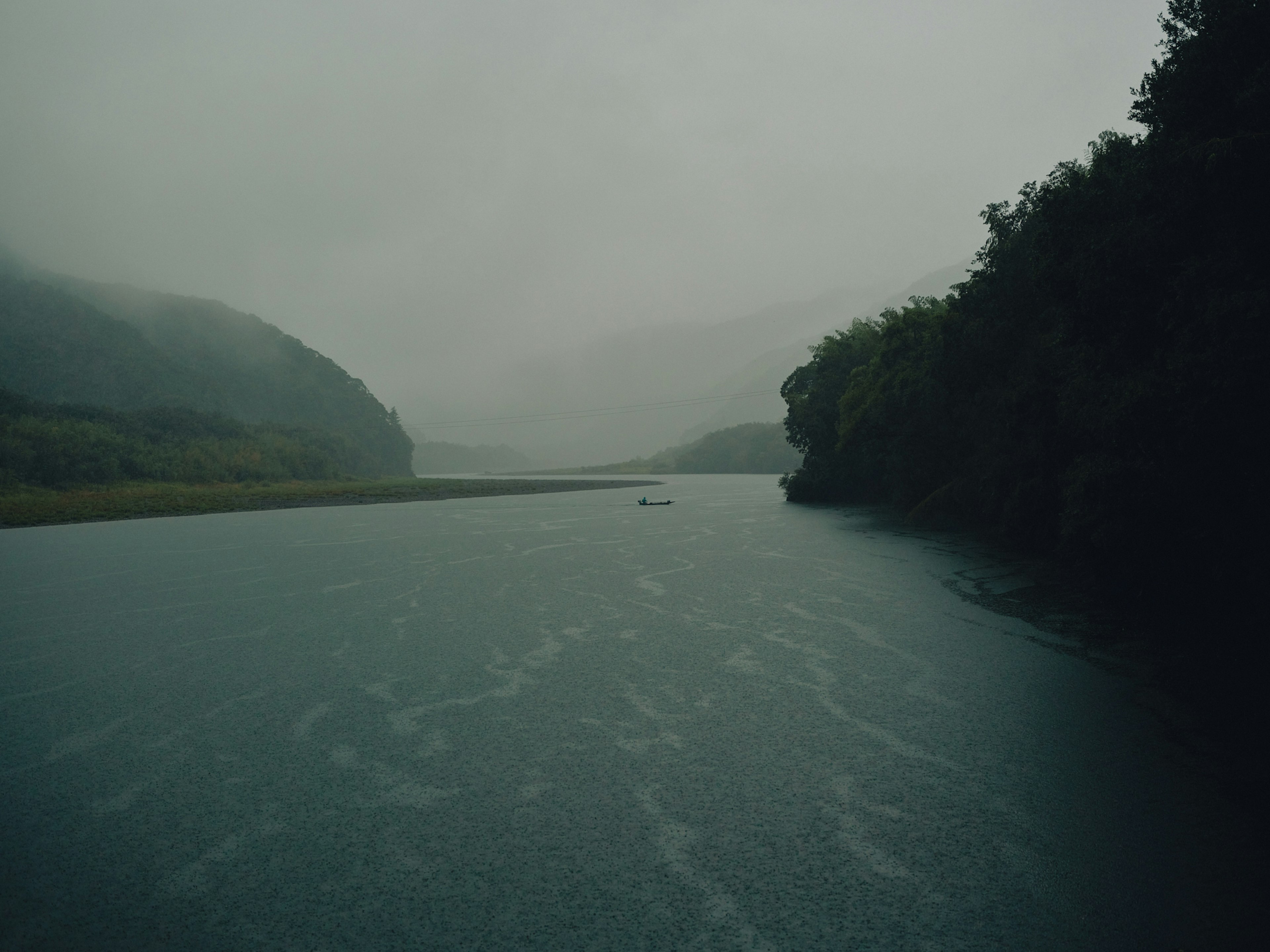 Ein ruhiger Fluss umgeben von nebligen Bergen und üppigem Grün