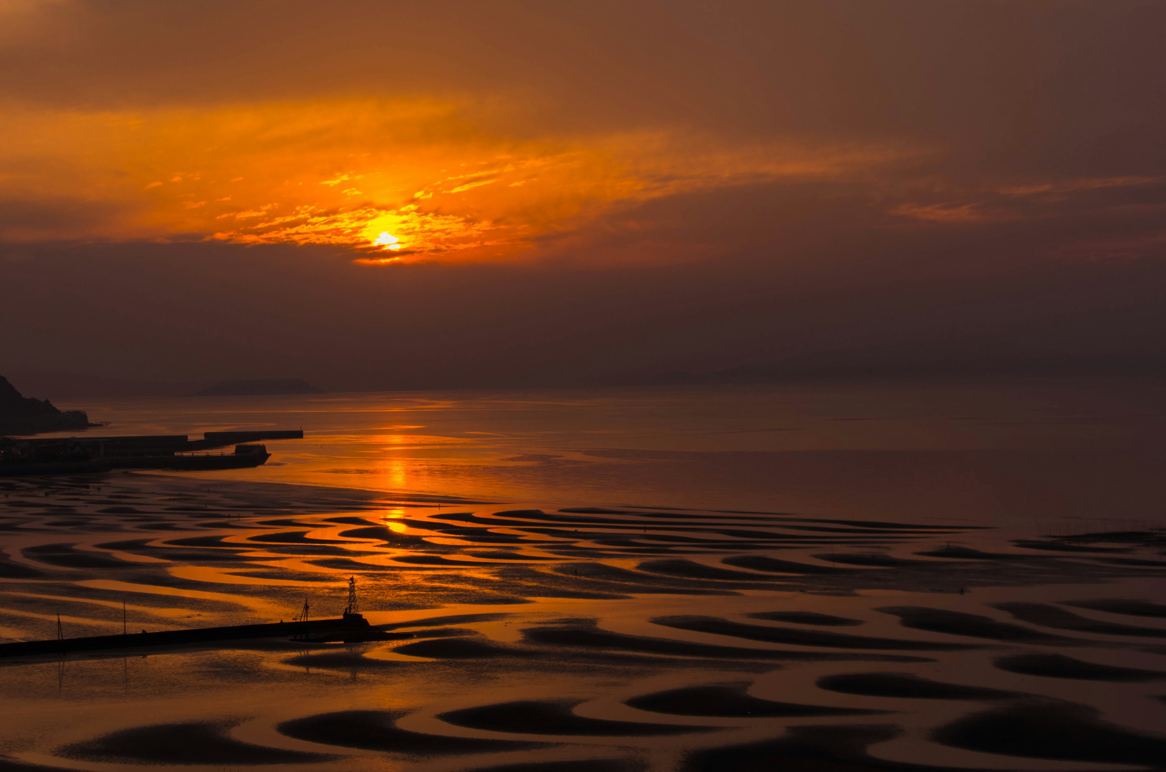 Schöne Landschaft mit Sonnenuntergang der sich im Meer spiegelt ausgeprägte Muster im Sand