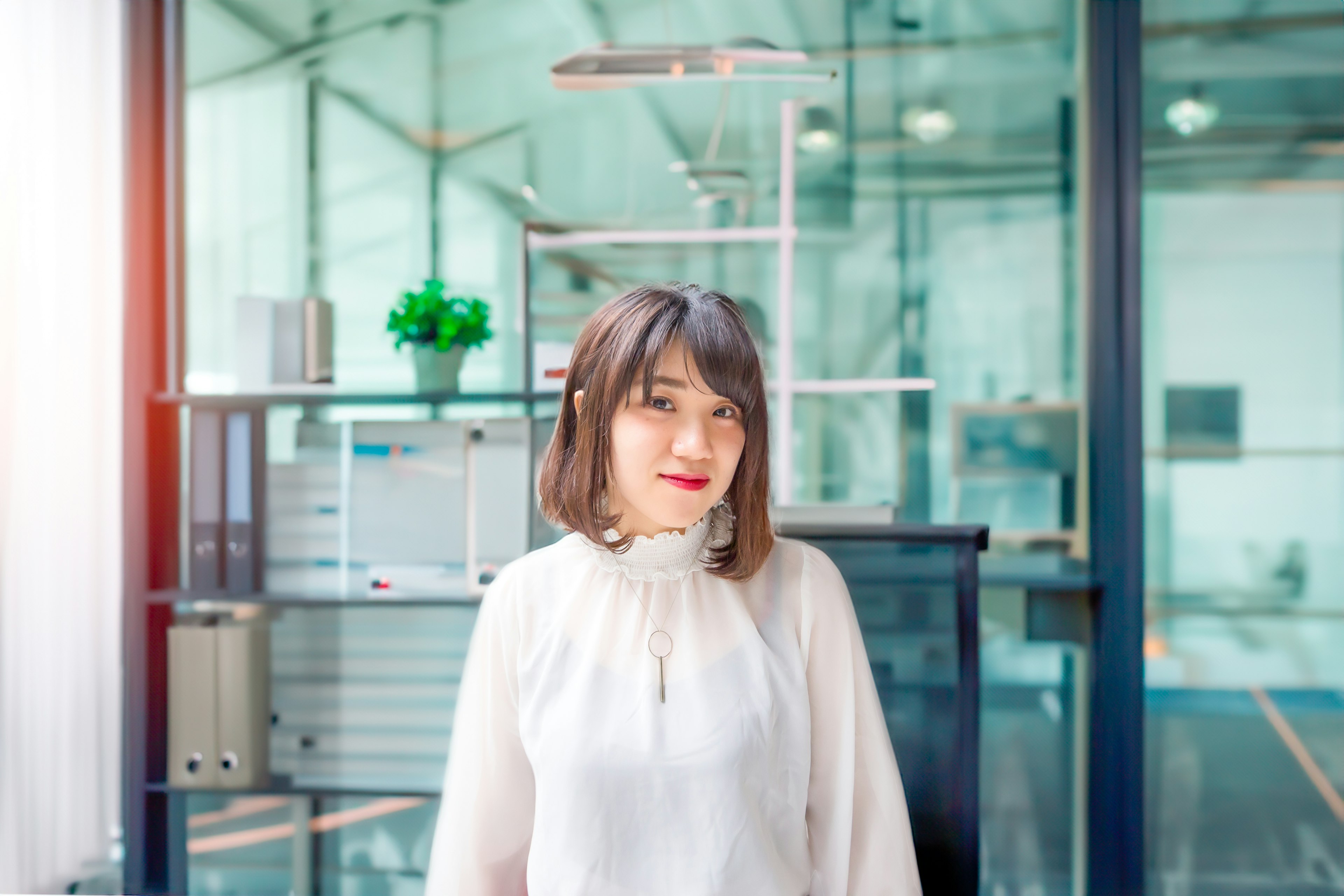 A woman smiling in a white blouse in a modern office setting