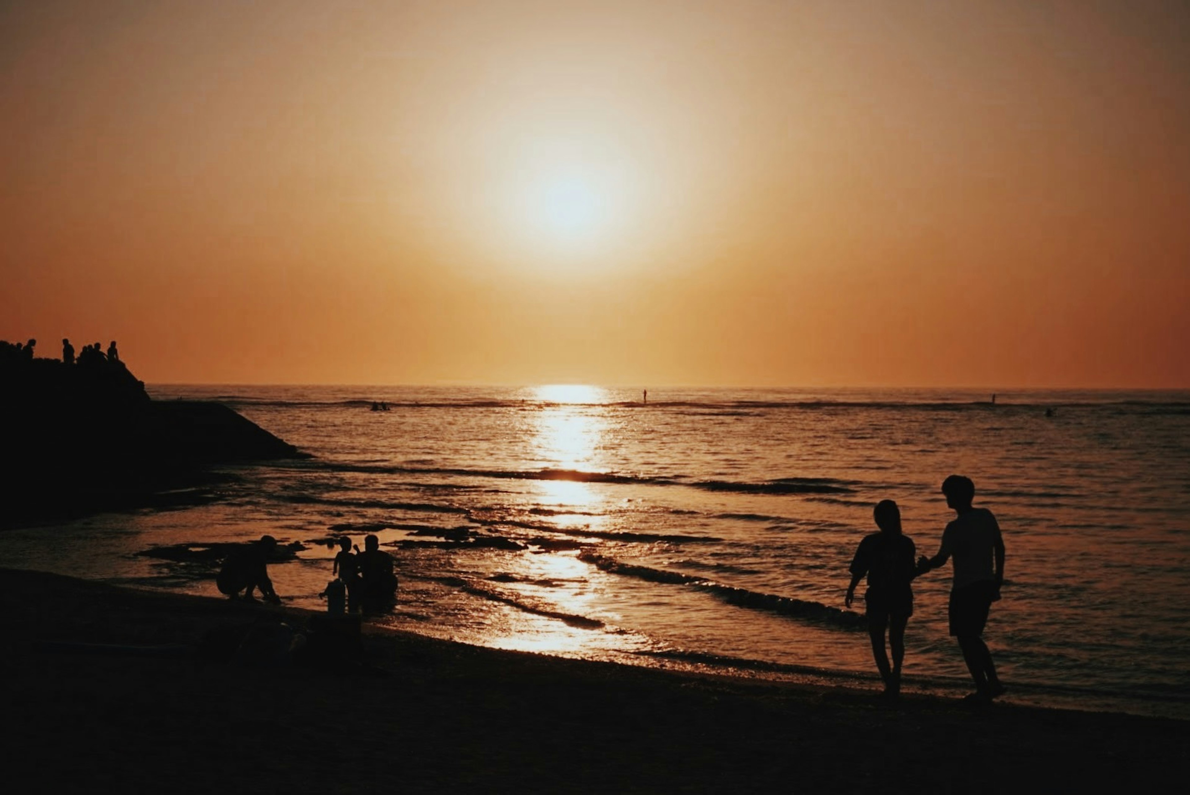 Silhouette d'un couple marchant main dans la main au coucher du soleil