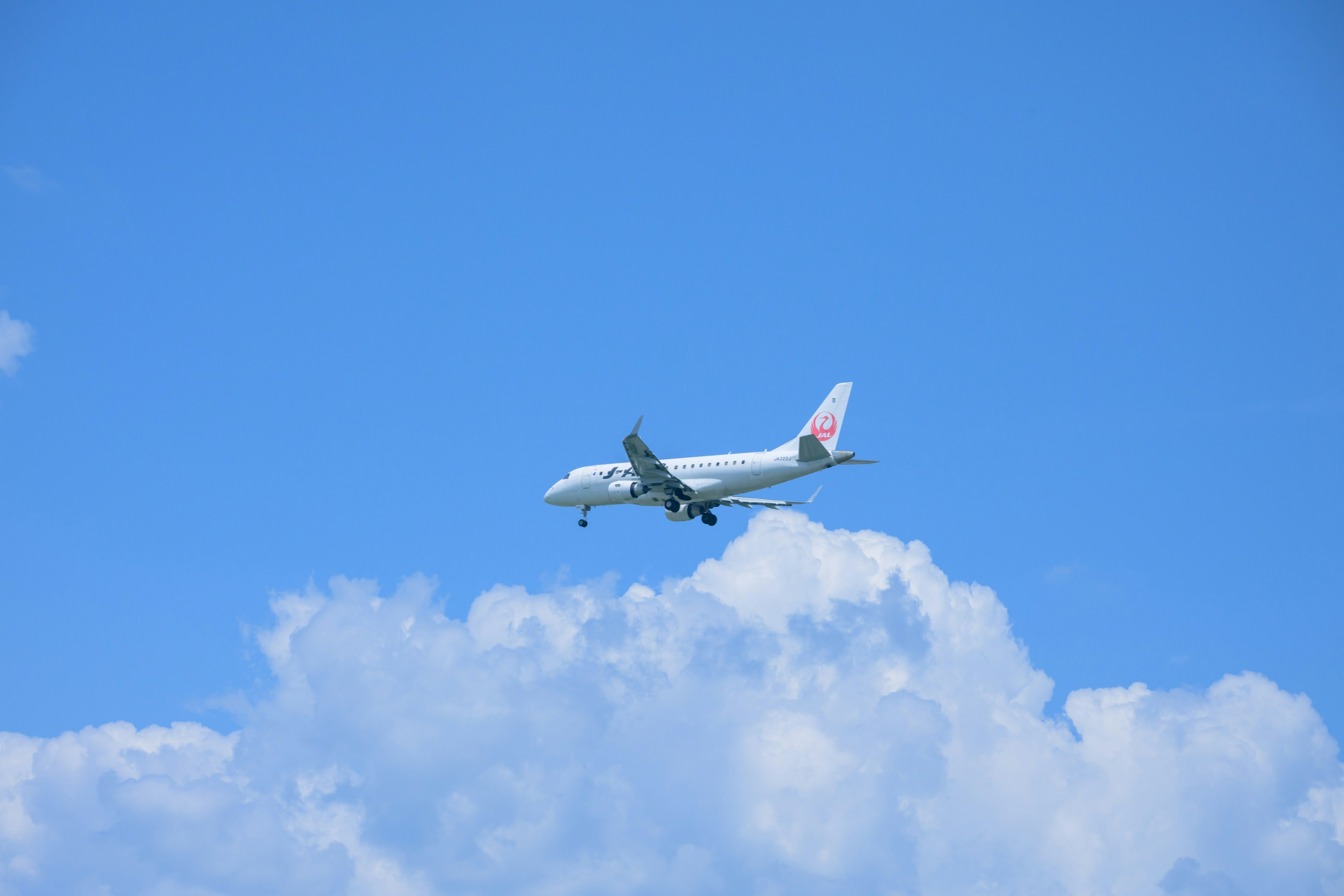 Airplane flying above white clouds in a blue sky