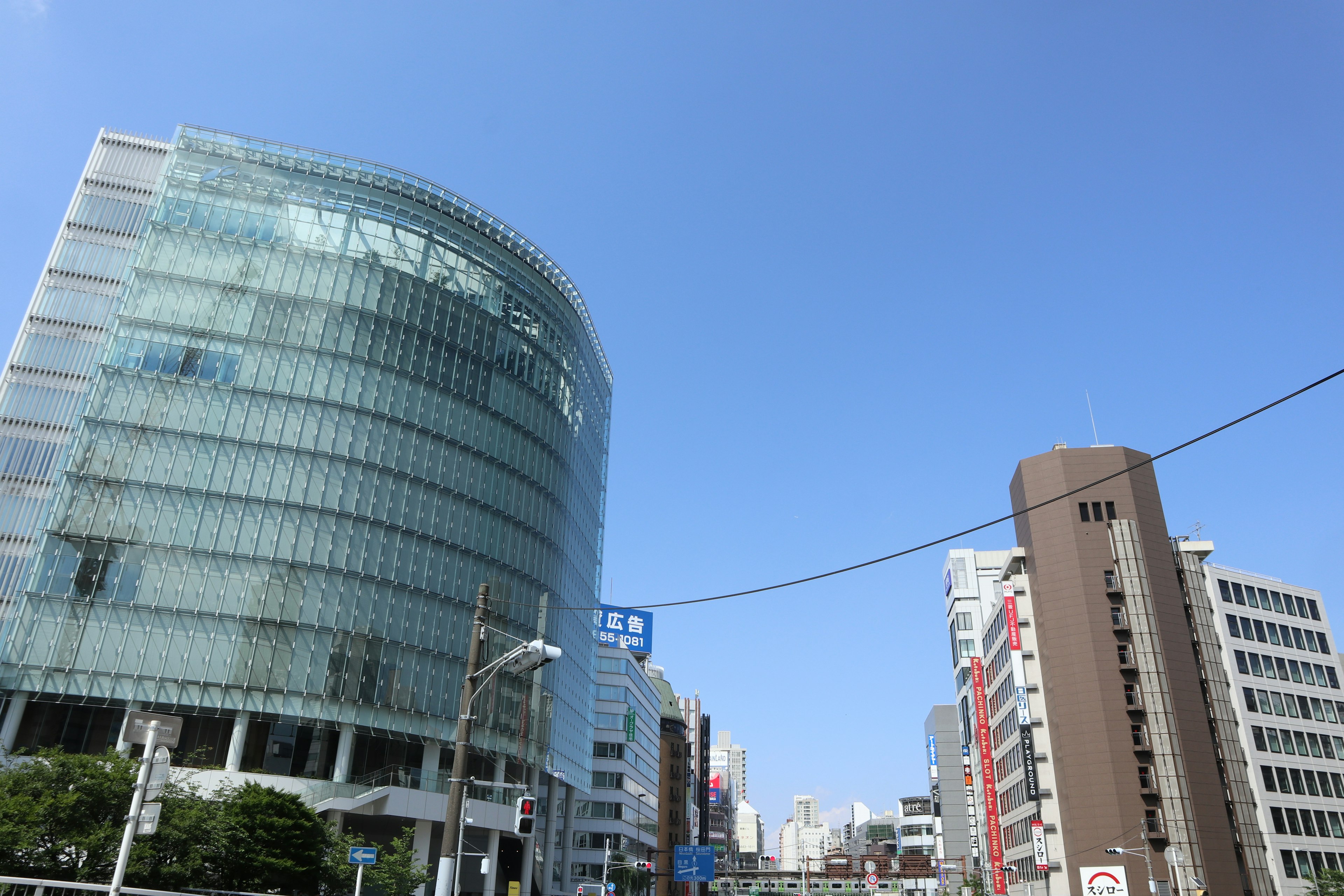 Bâtiment moderne en verre sous un ciel bleu clair avec un paysage urbain environnant