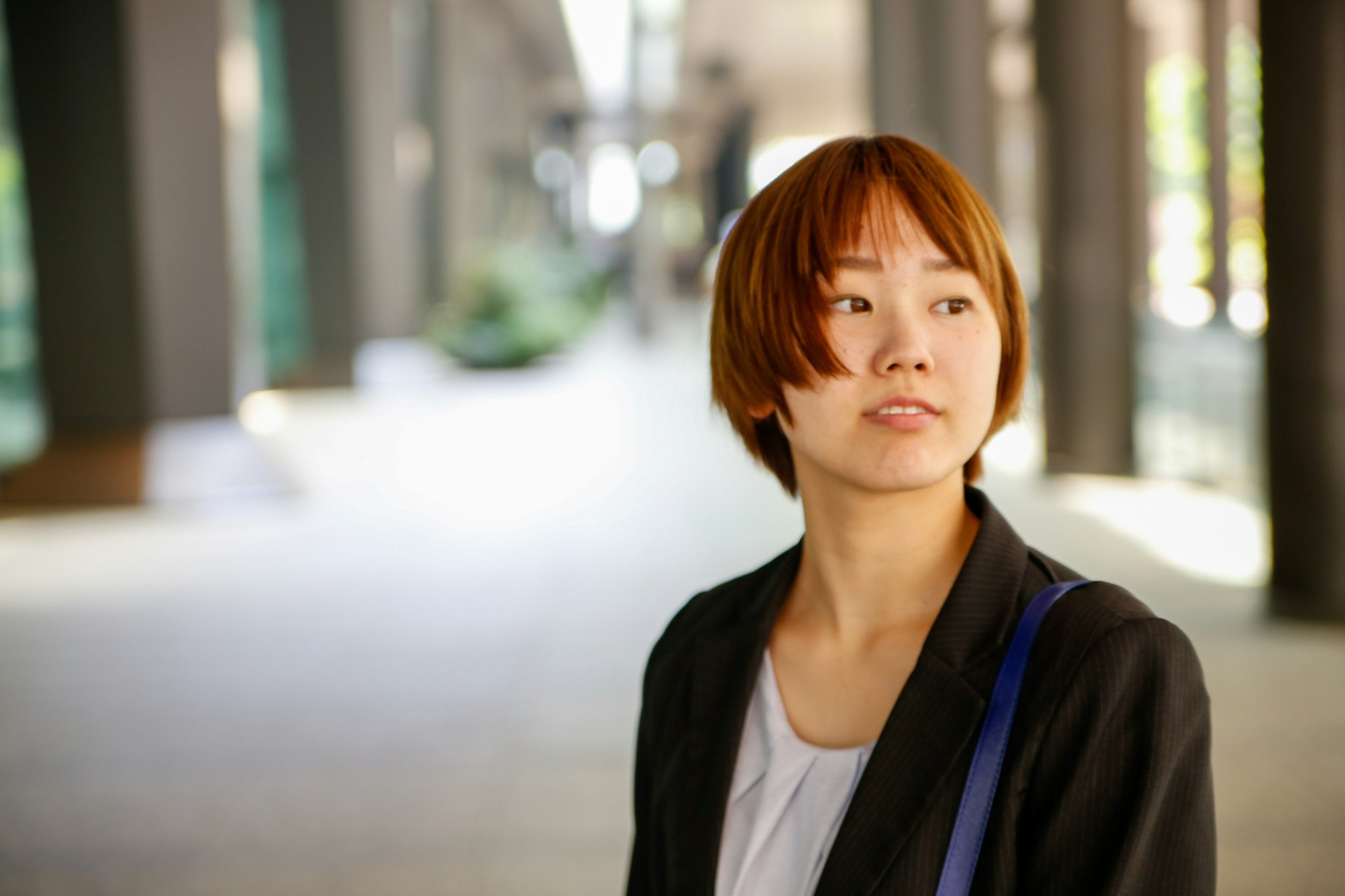 A woman gazing thoughtfully in an urban setting with columns in the background