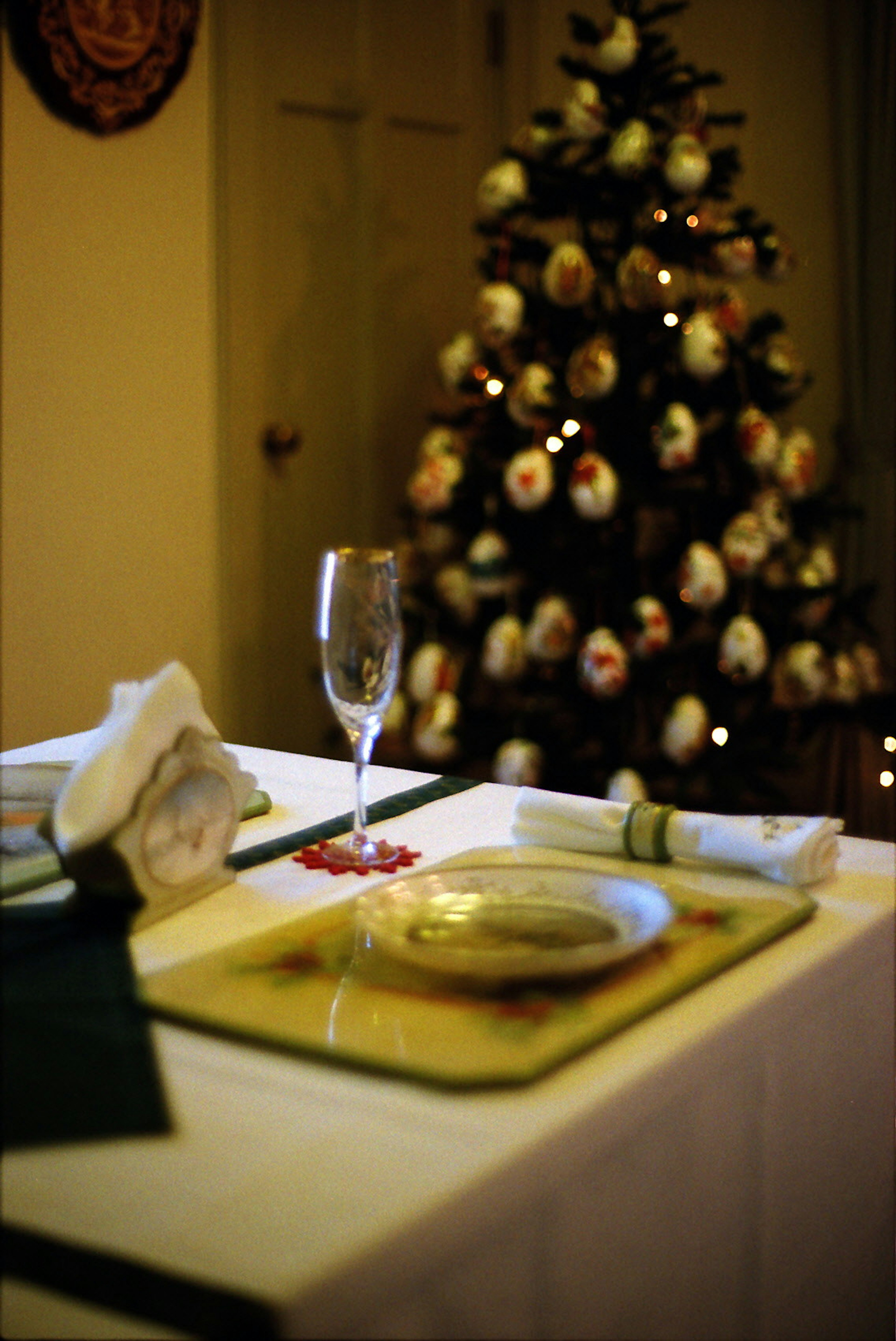 Impostazione della tavola di Natale con un bicchiere di champagne e un albero decorato