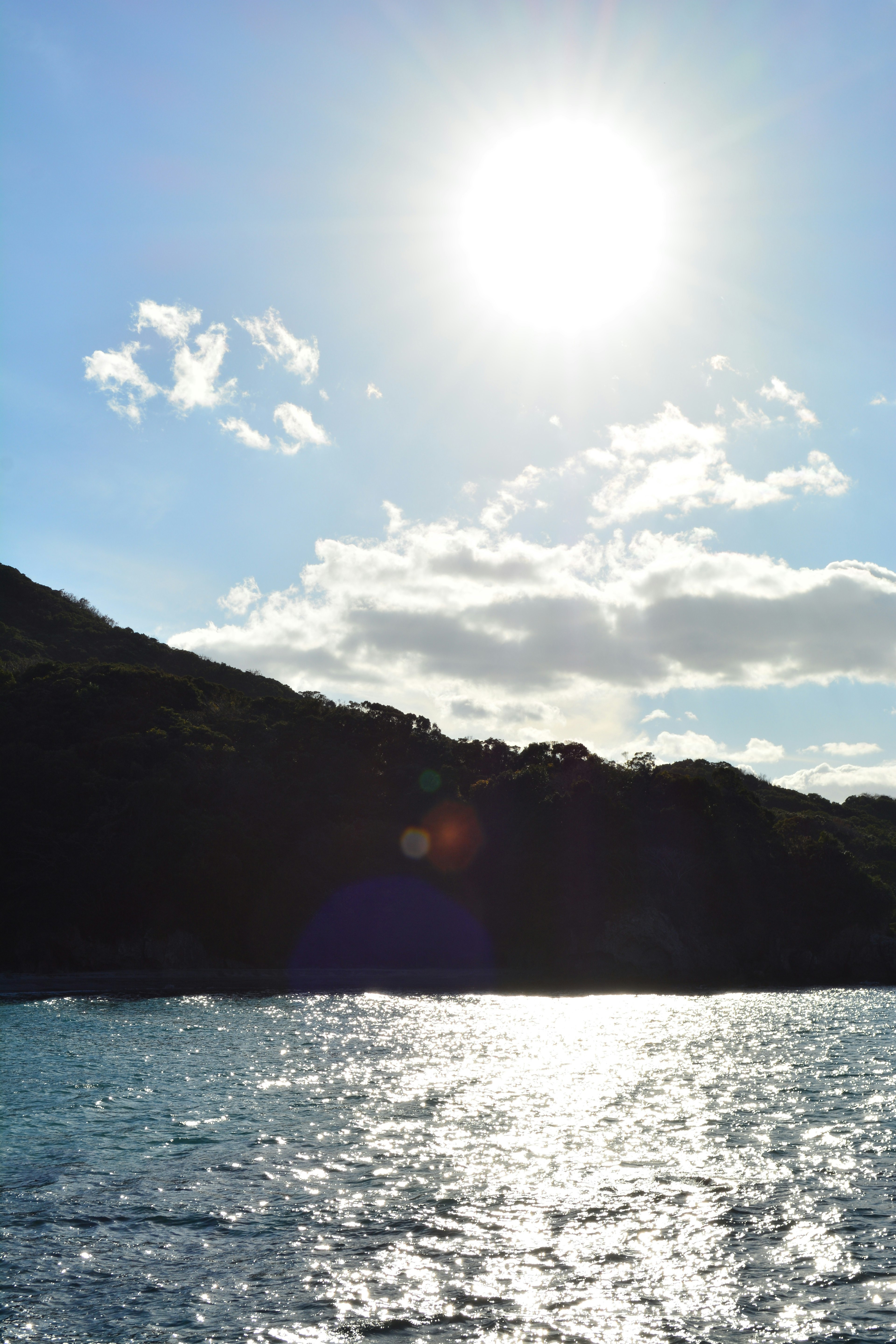 Paysage avec mer bleue et lumière du soleil se reflétant Silhouette de montagne visible