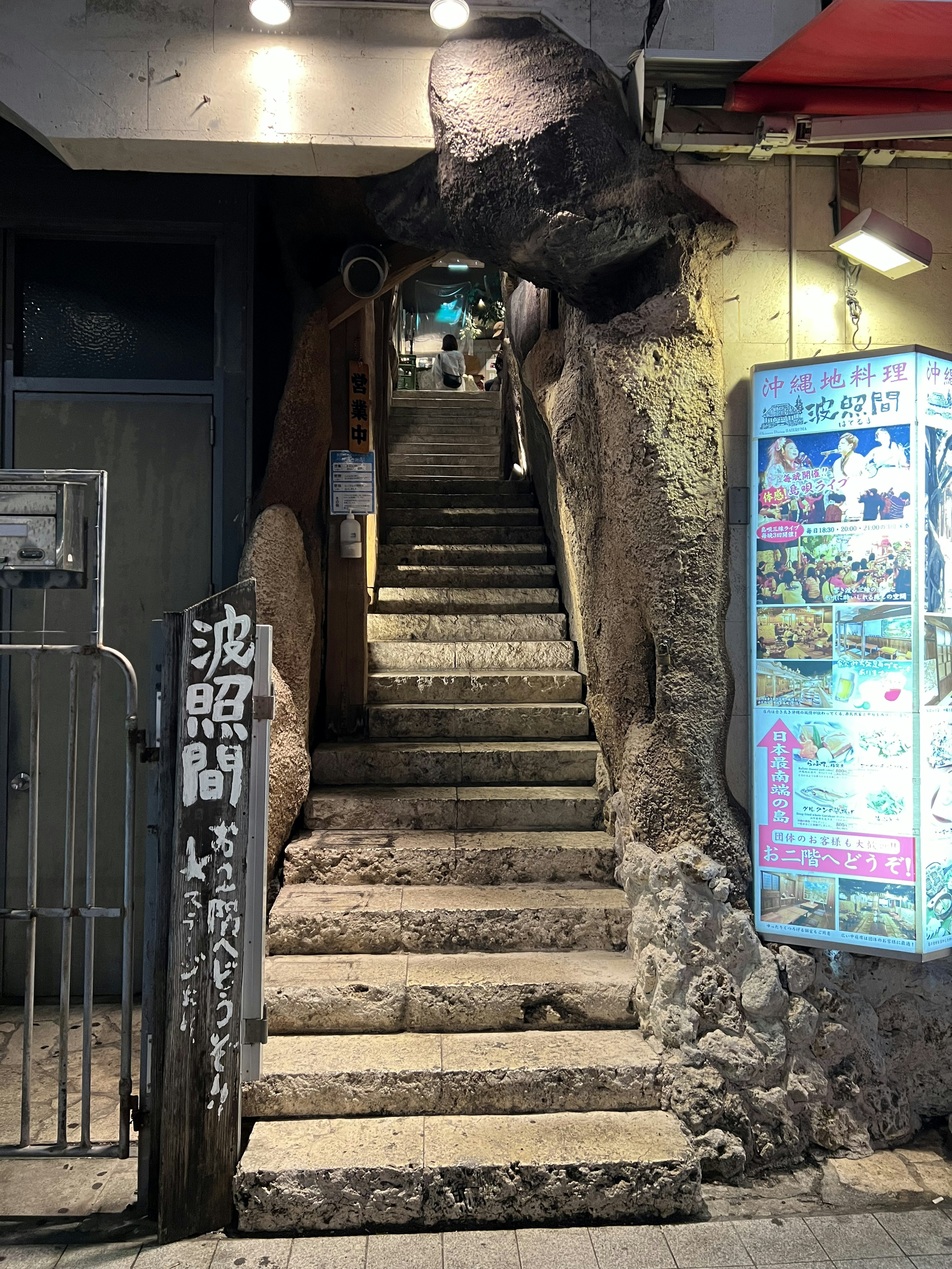 Photo d'un escalier entouré de roches avec un éclairage lumineux et des publicités