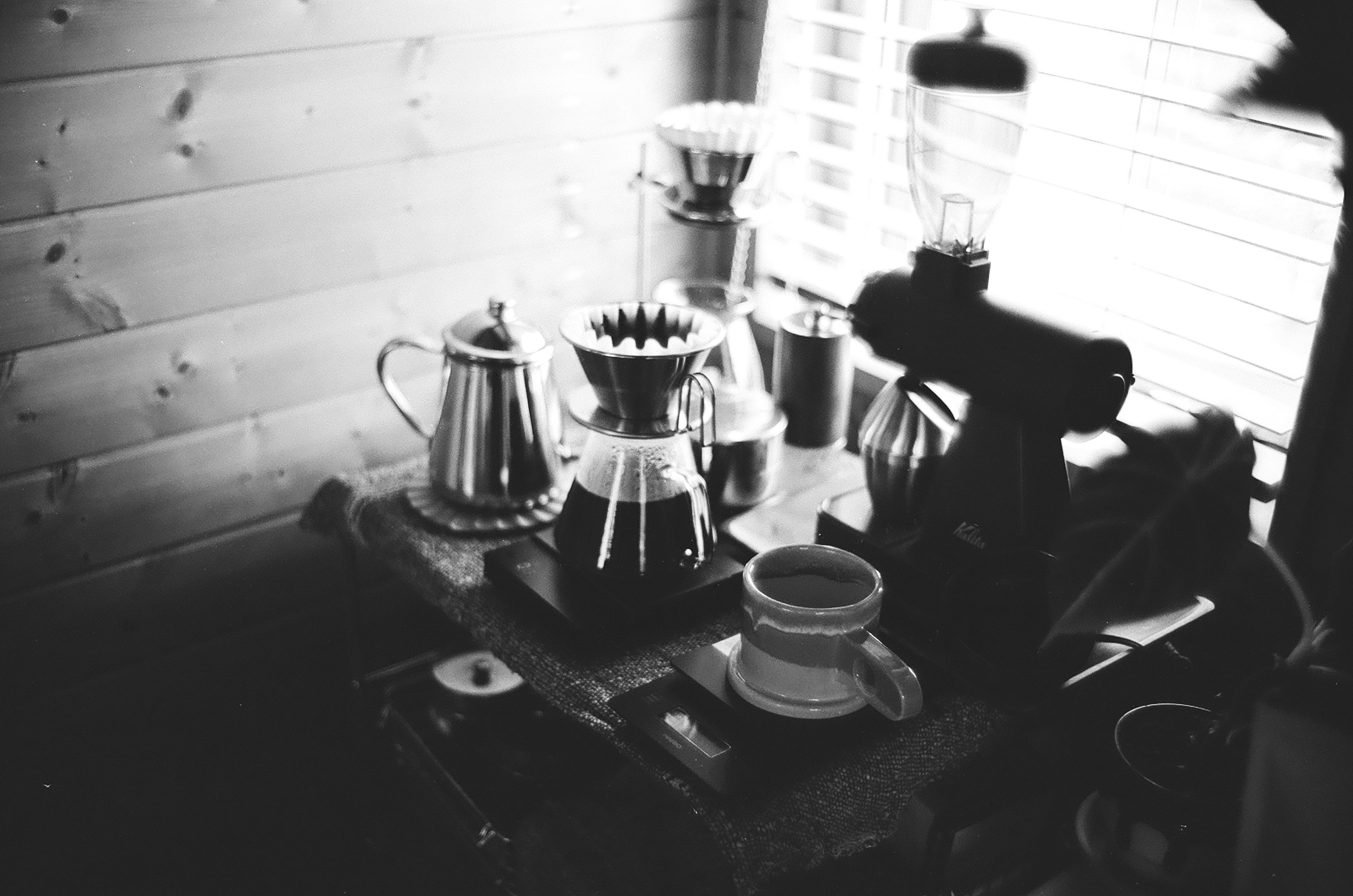 Schwarzweißfoto von Kaffeebereitungsgeräten auf einem Holztisch