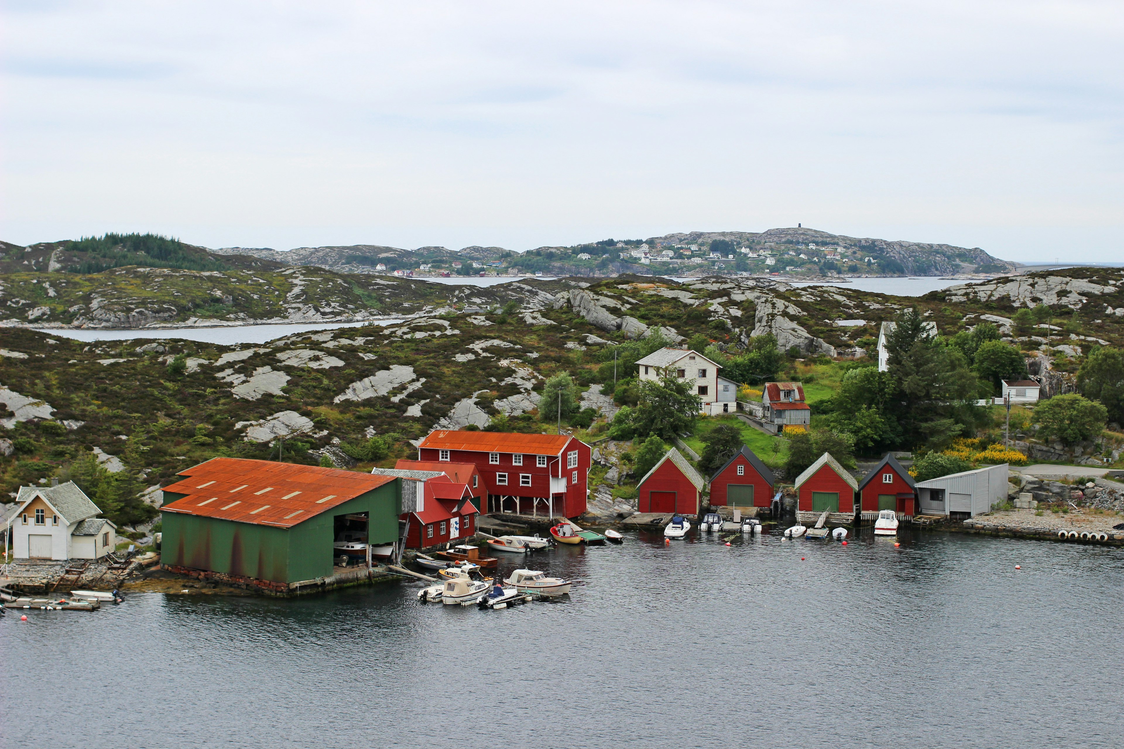 Scenic view featuring red cabins and a green building near the water