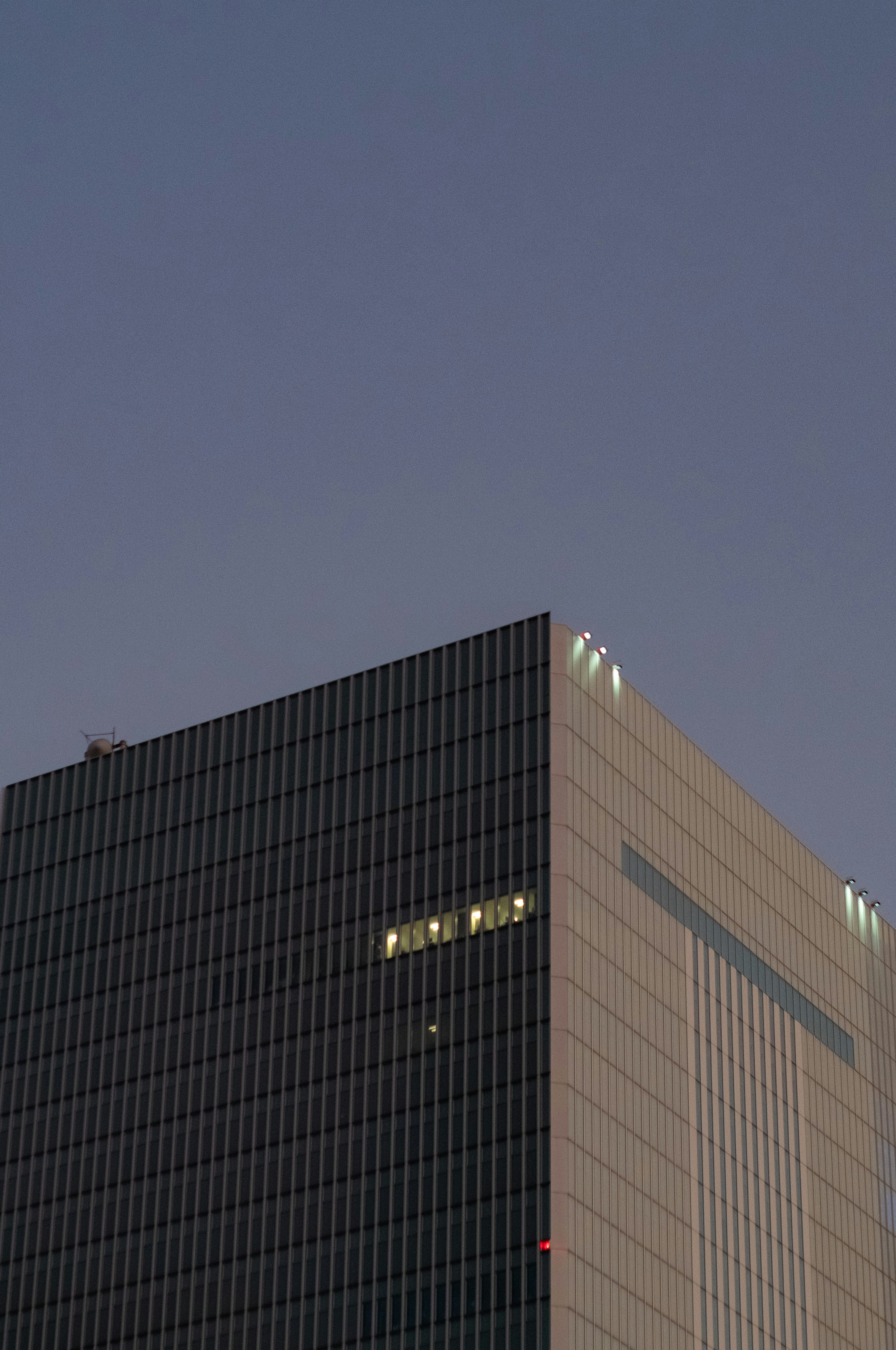 Partie d'un gratte-ciel illuminée contre le ciel du crépuscule