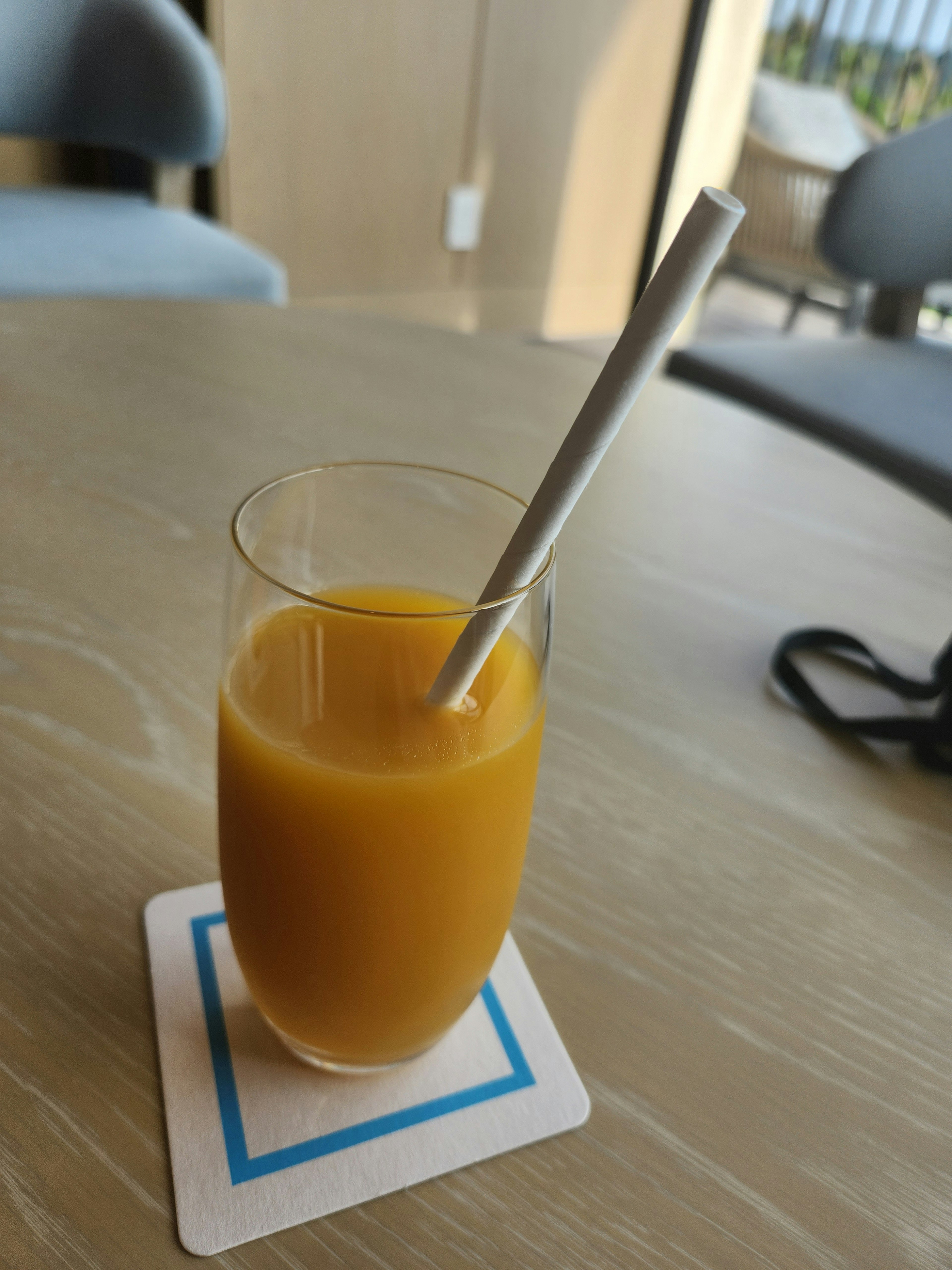 Ein Glas Orangensaft mit einem Strohhalm auf einem Untersetzer auf einem Tisch