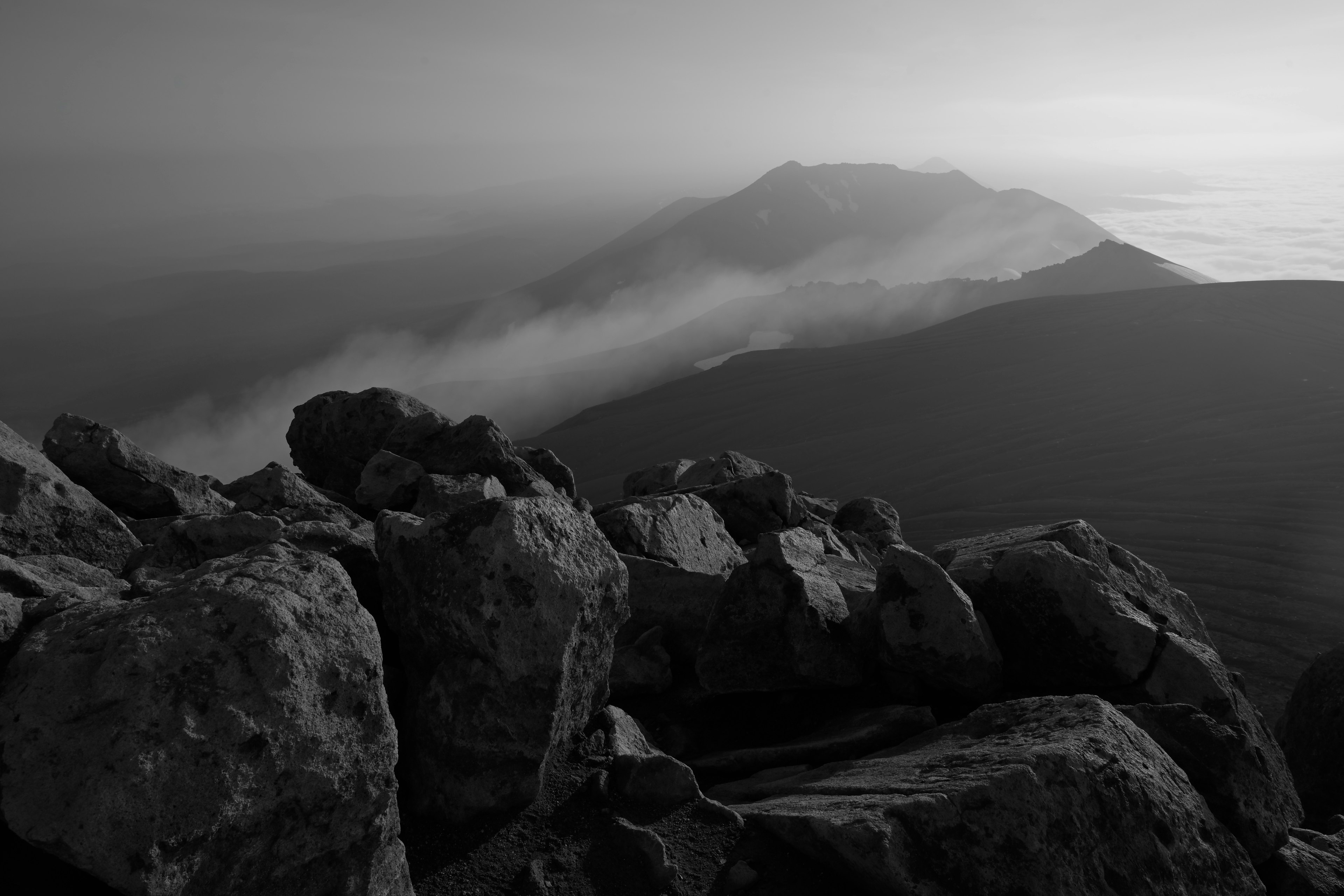 Gambar hitam putih pemandangan gunung dengan fokus dekat batu