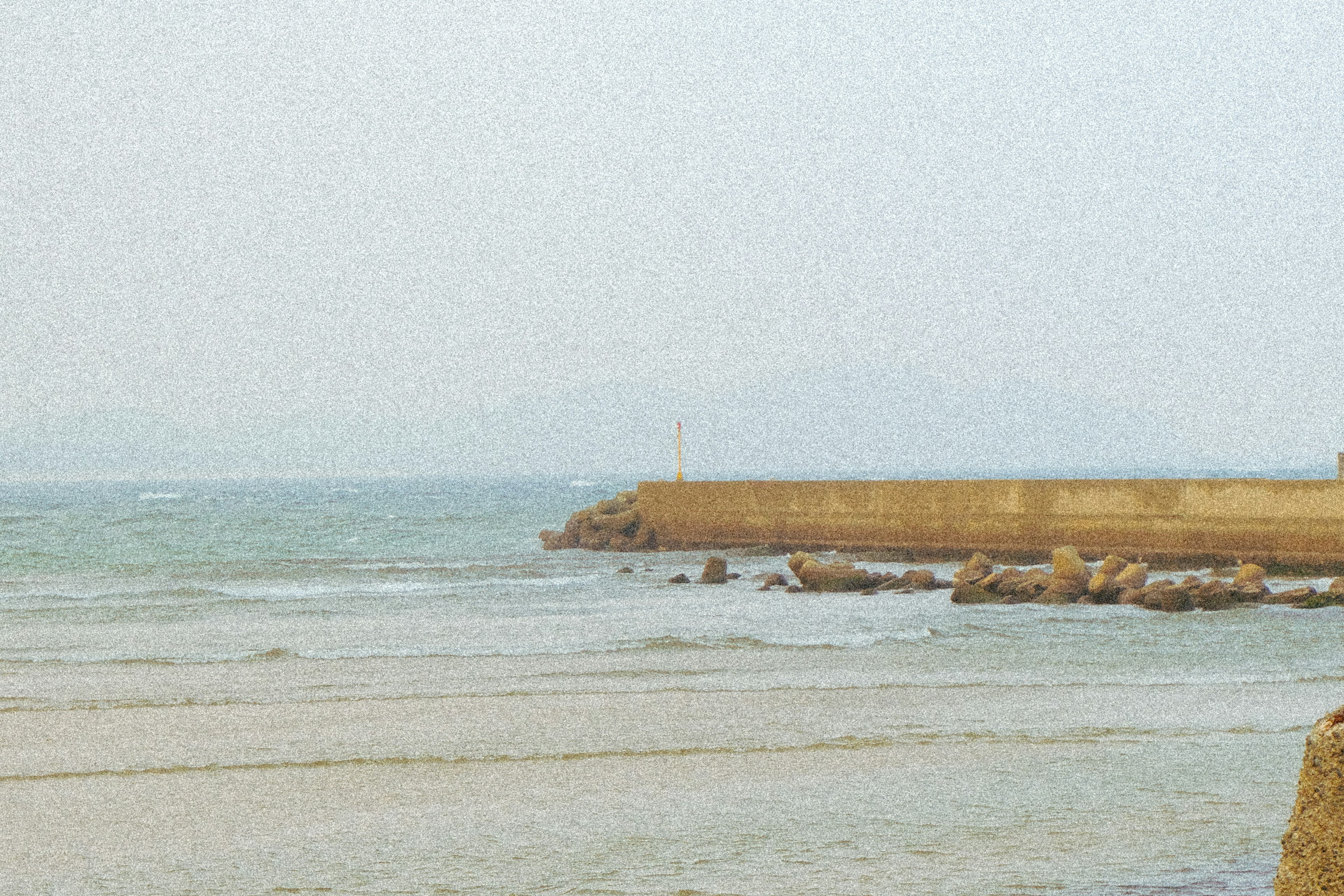 Vista costera con un rompeolas y olas suaves