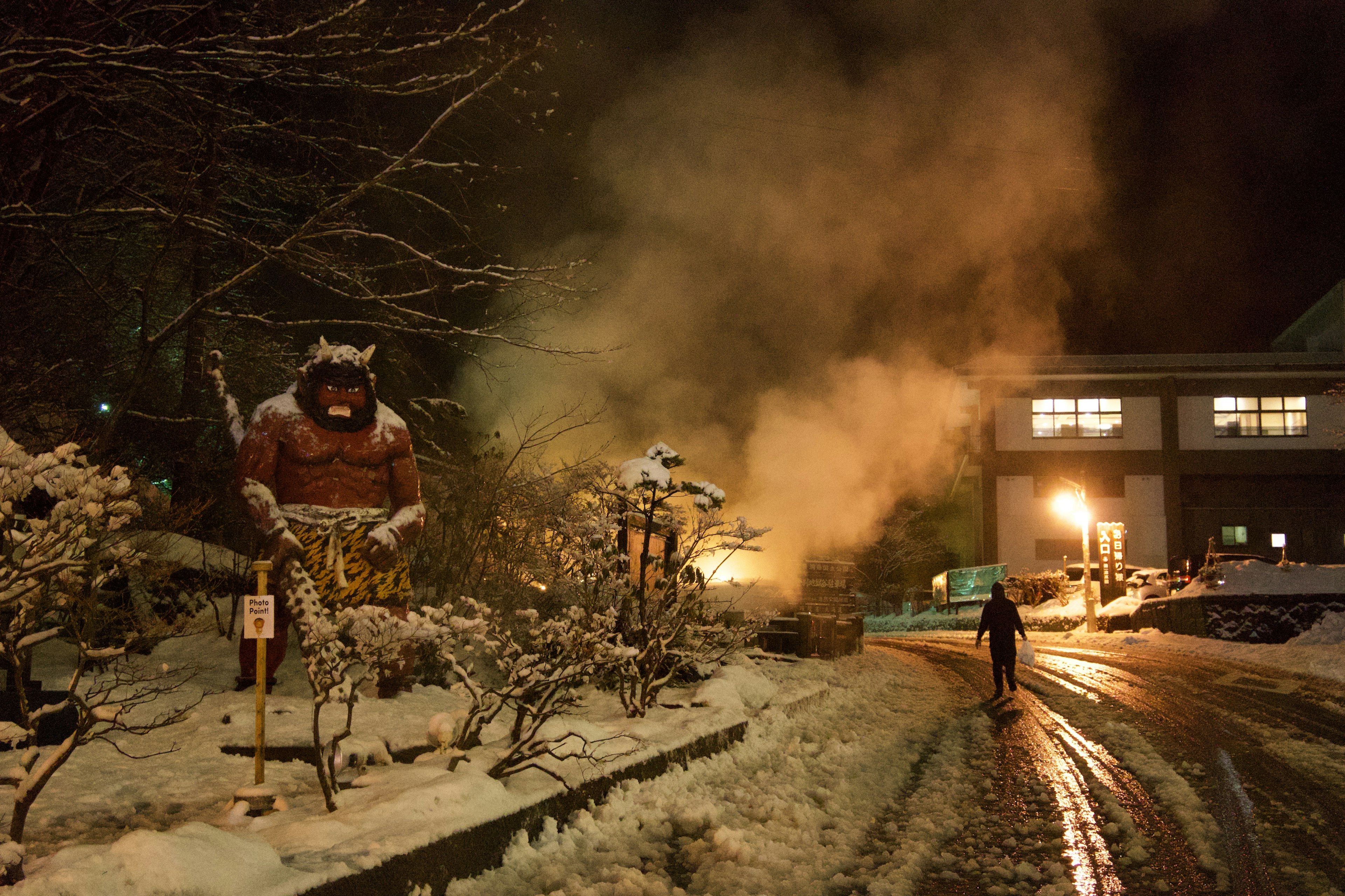 雪中的温泉区夜景，巨型雕像和升起的蒸汽