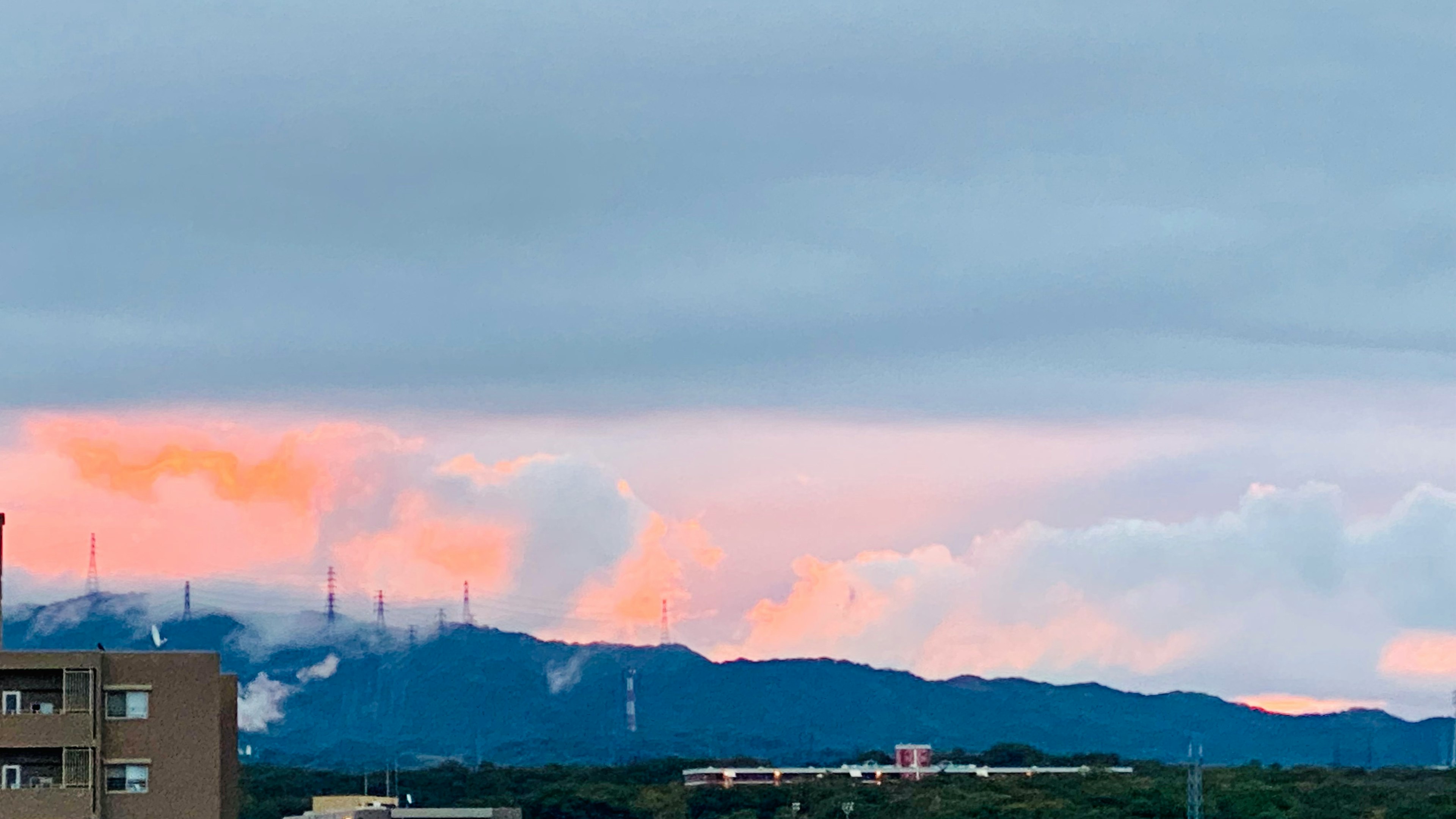 山の上にオレンジ色の雲と灰色の空が広がる風景