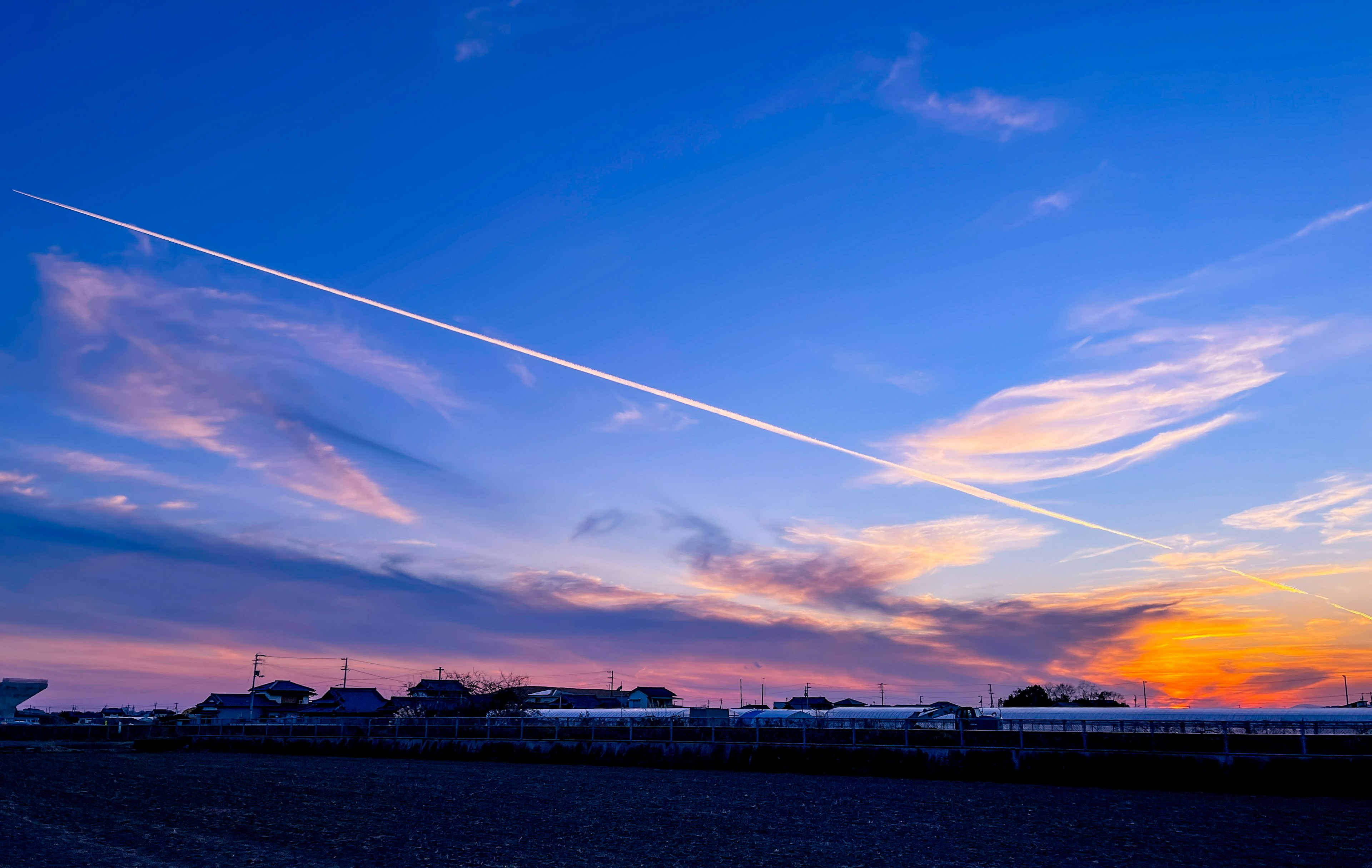 Bellissimo tramonto con nuvole e scie di aerei in un cielo blu