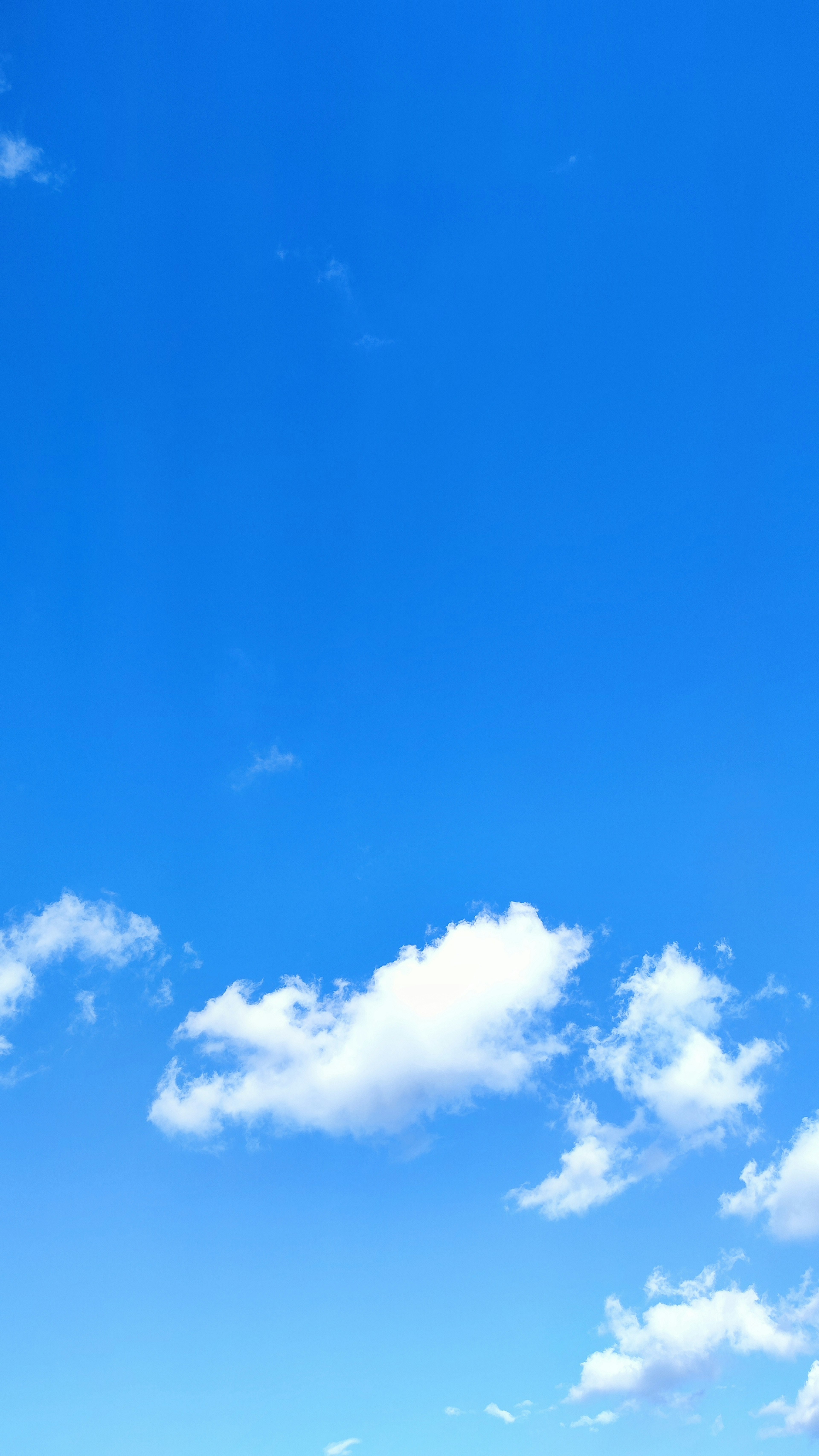 Klarer blauer Himmel mit flauschigen weißen Wolken