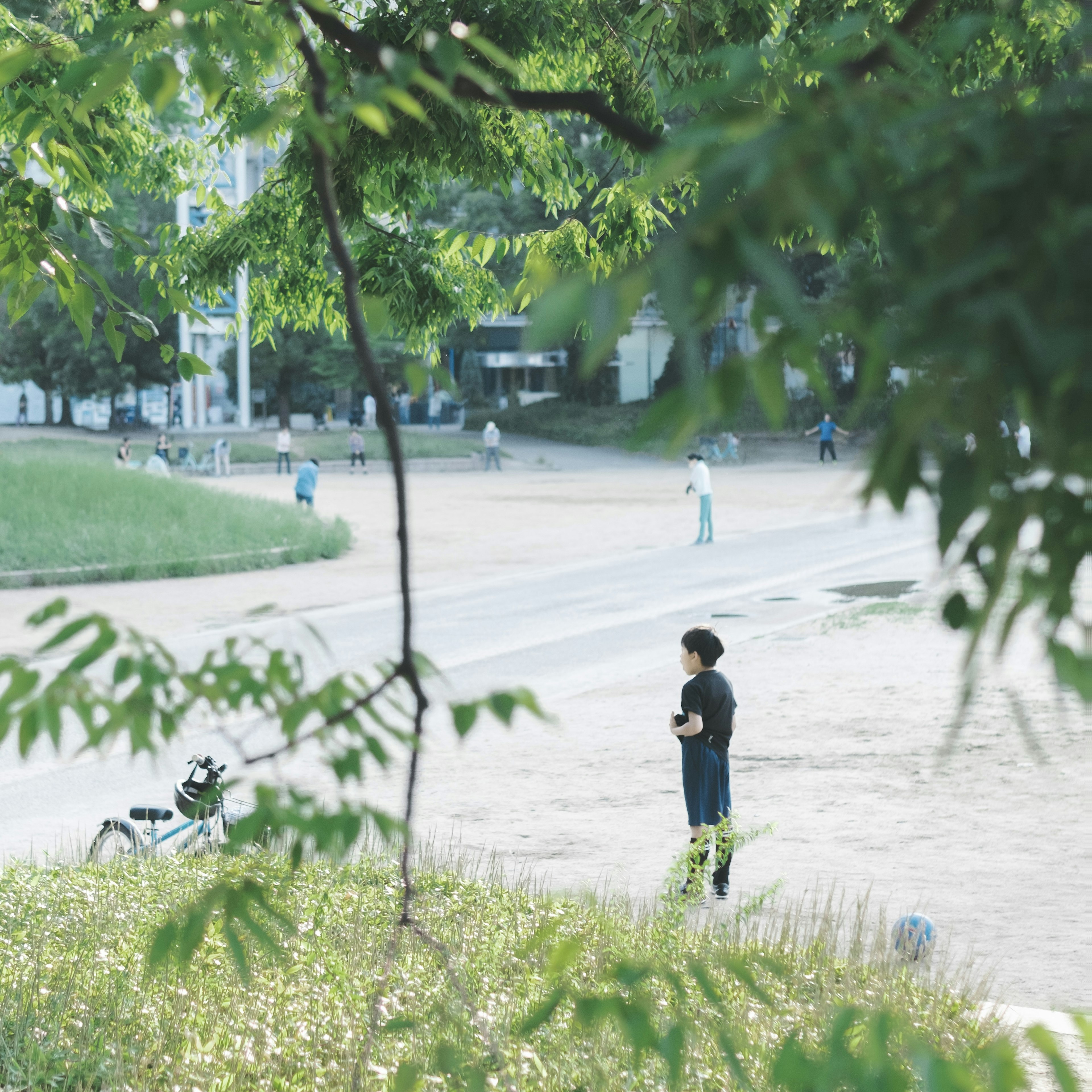 緑豊かな公園で立っている人物と背景の人々