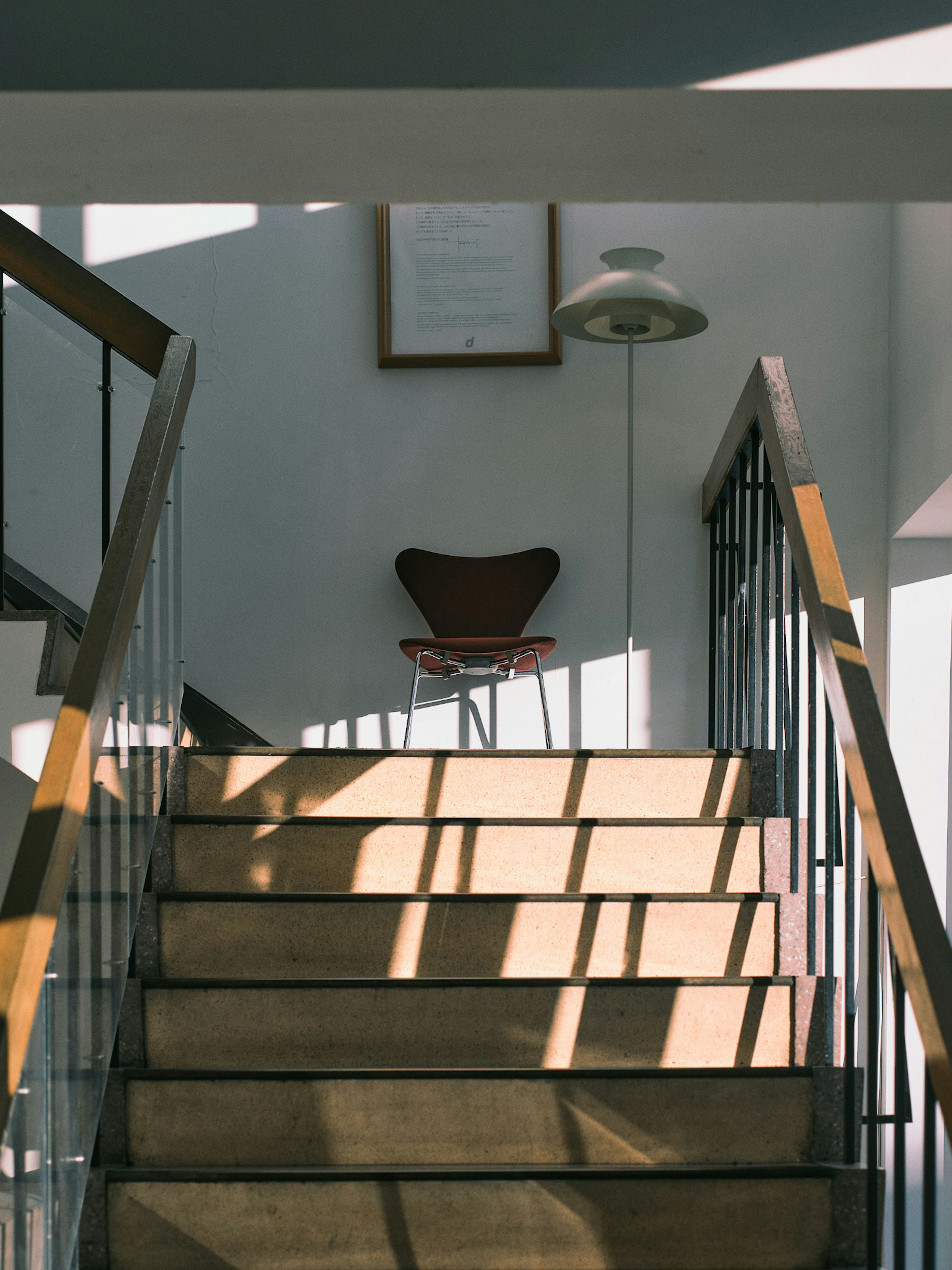 Una escena interior simple con una silla y una lámpara en las escaleras