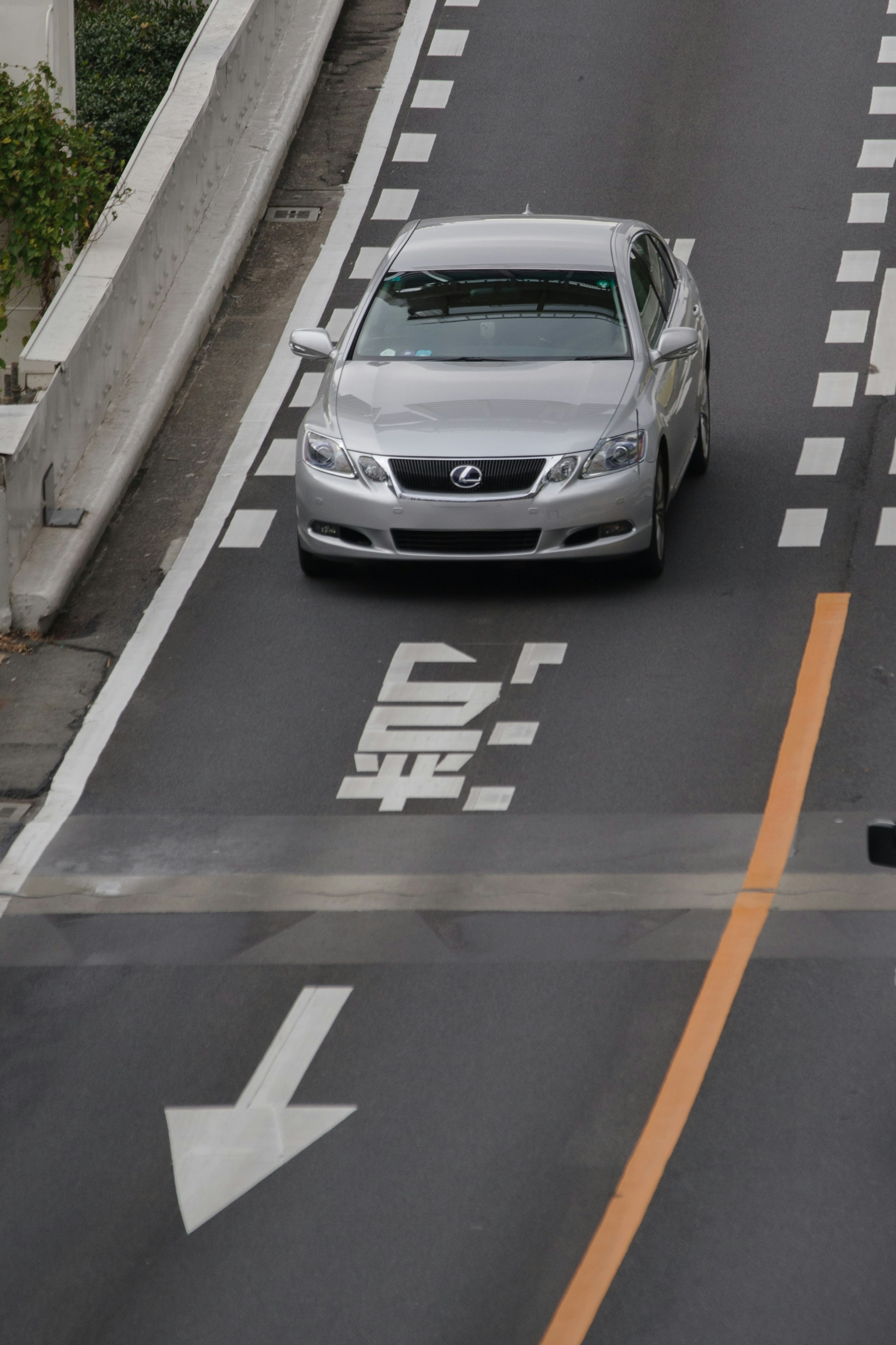 一辆银色汽车在道路上行驶，路面有可见的车道标记