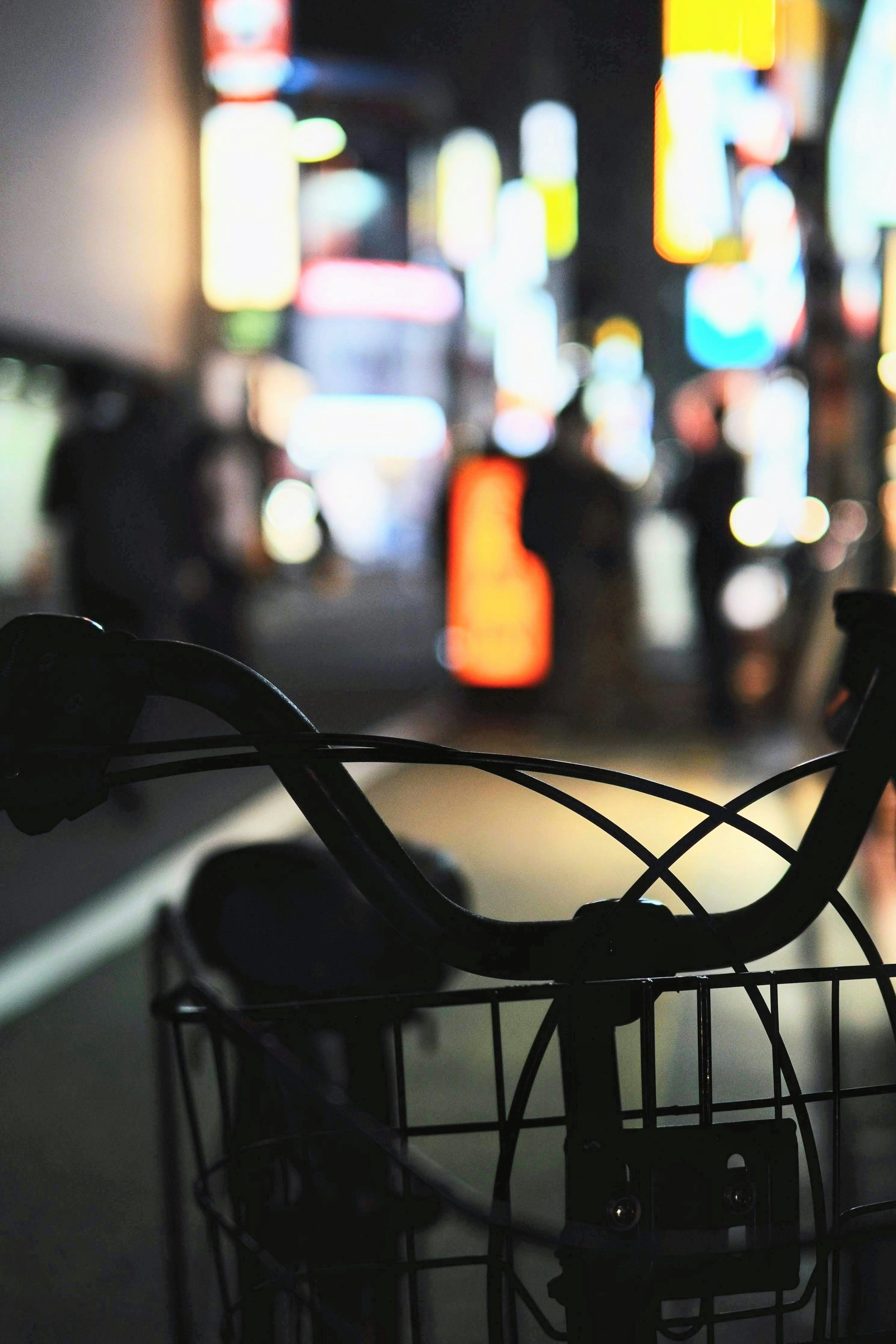 Bicycle handlebars with a blurred cityscape at night