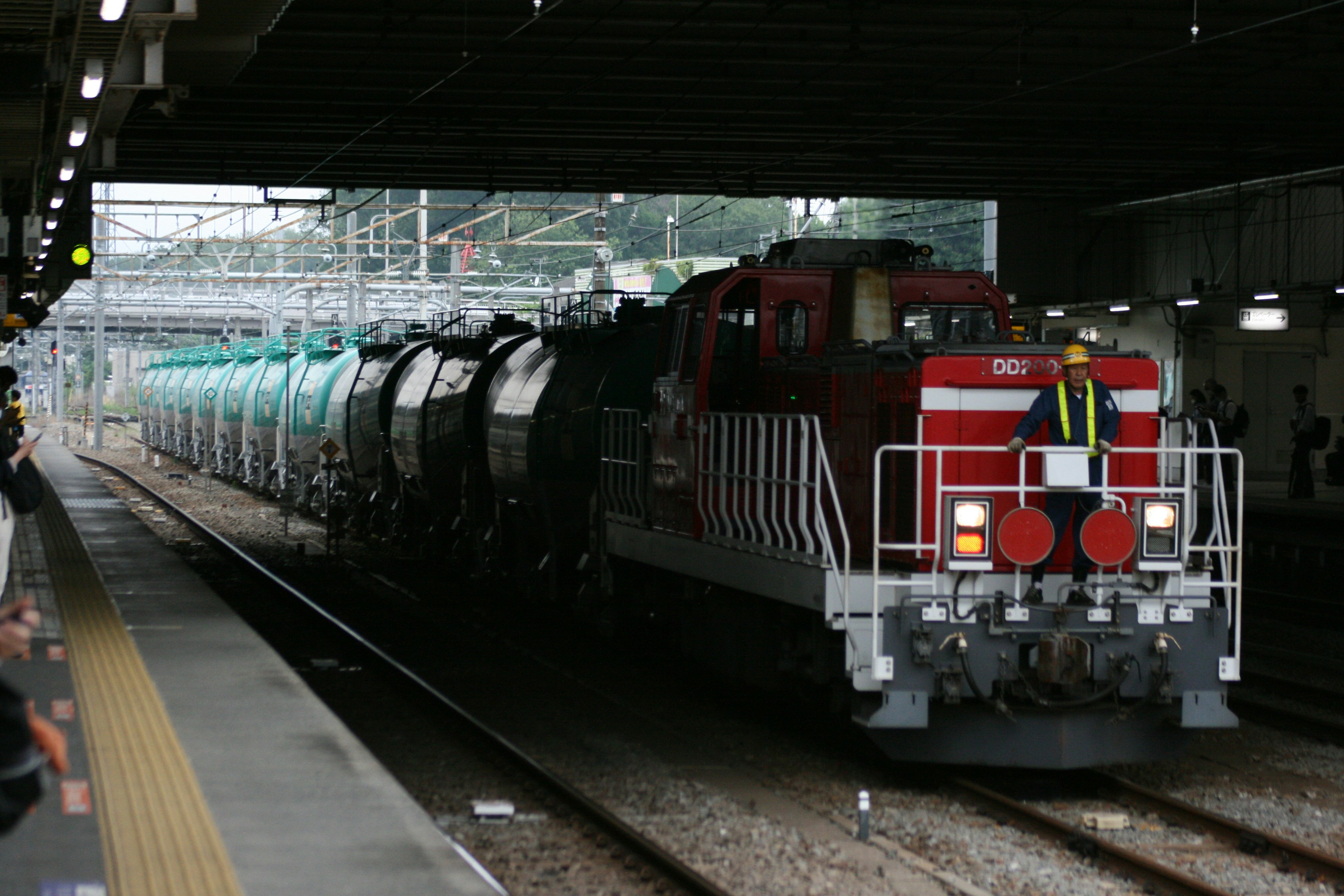 Lokomotif merah dan putih menarik kereta barang di stasiun