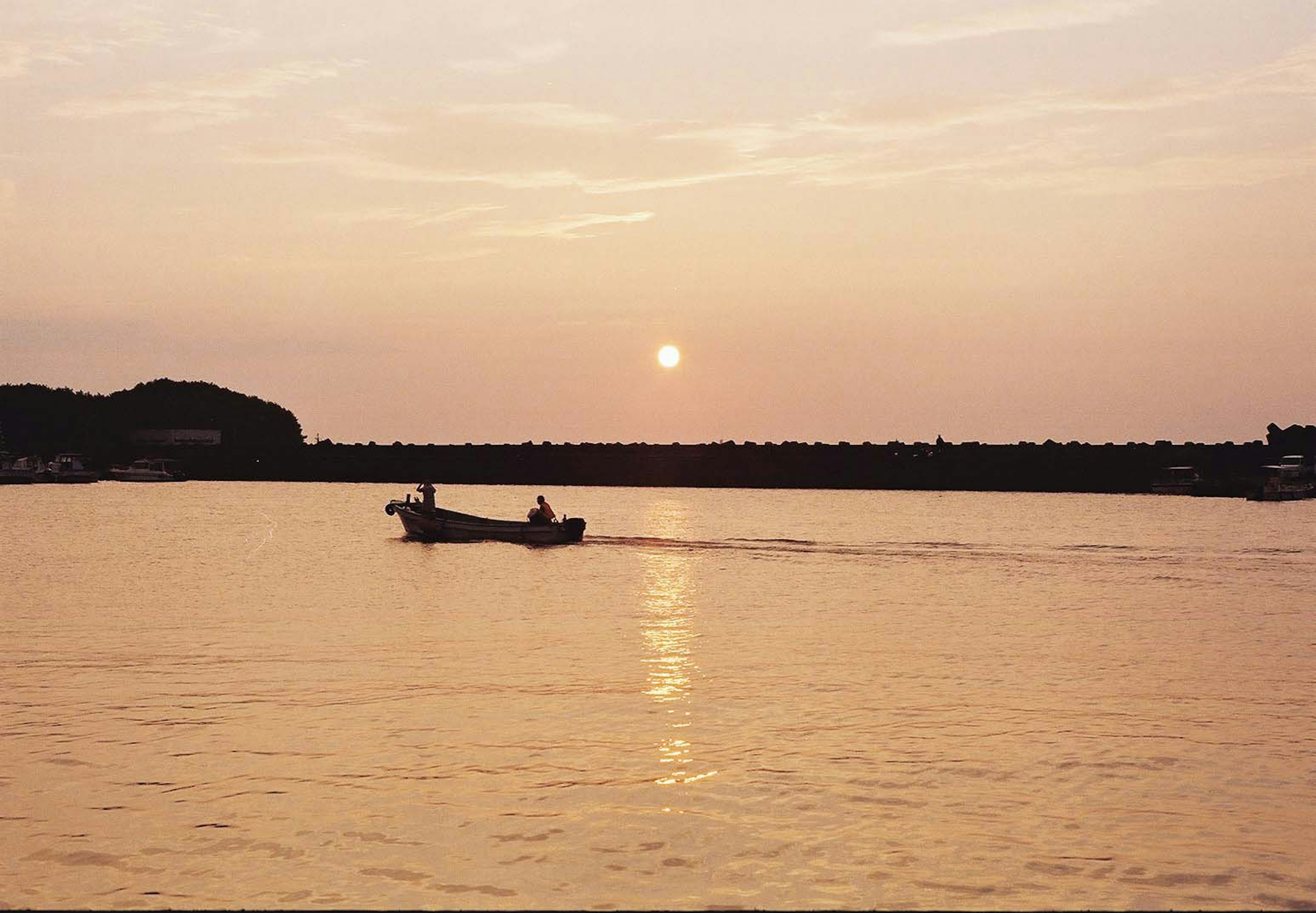 ทิวทัศน์ที่สวยงามของพระอาทิตย์ตกเหนือทะเลพร้อมเรือเล็ก