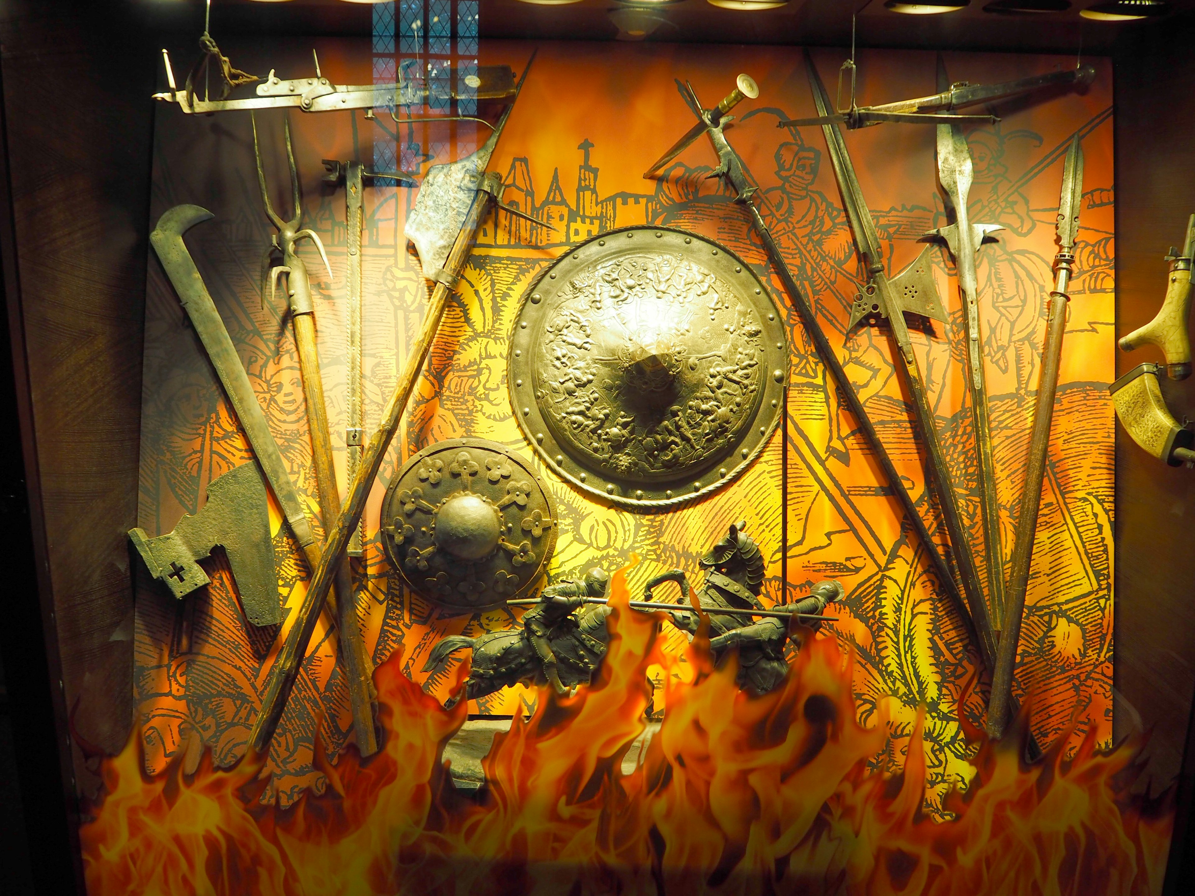 Display of weapons and shields against a fiery background