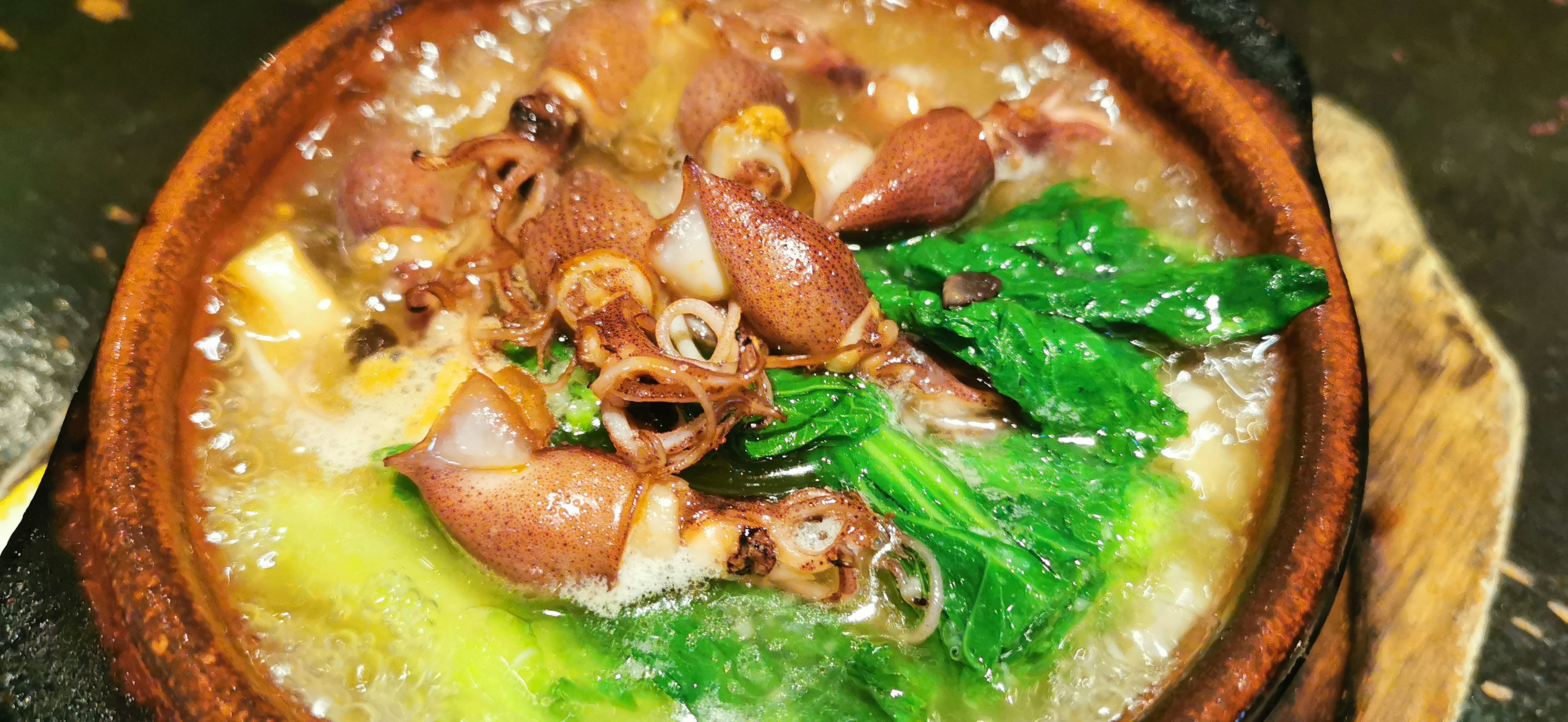 Seafood dish simmered in a pot with green vegetables