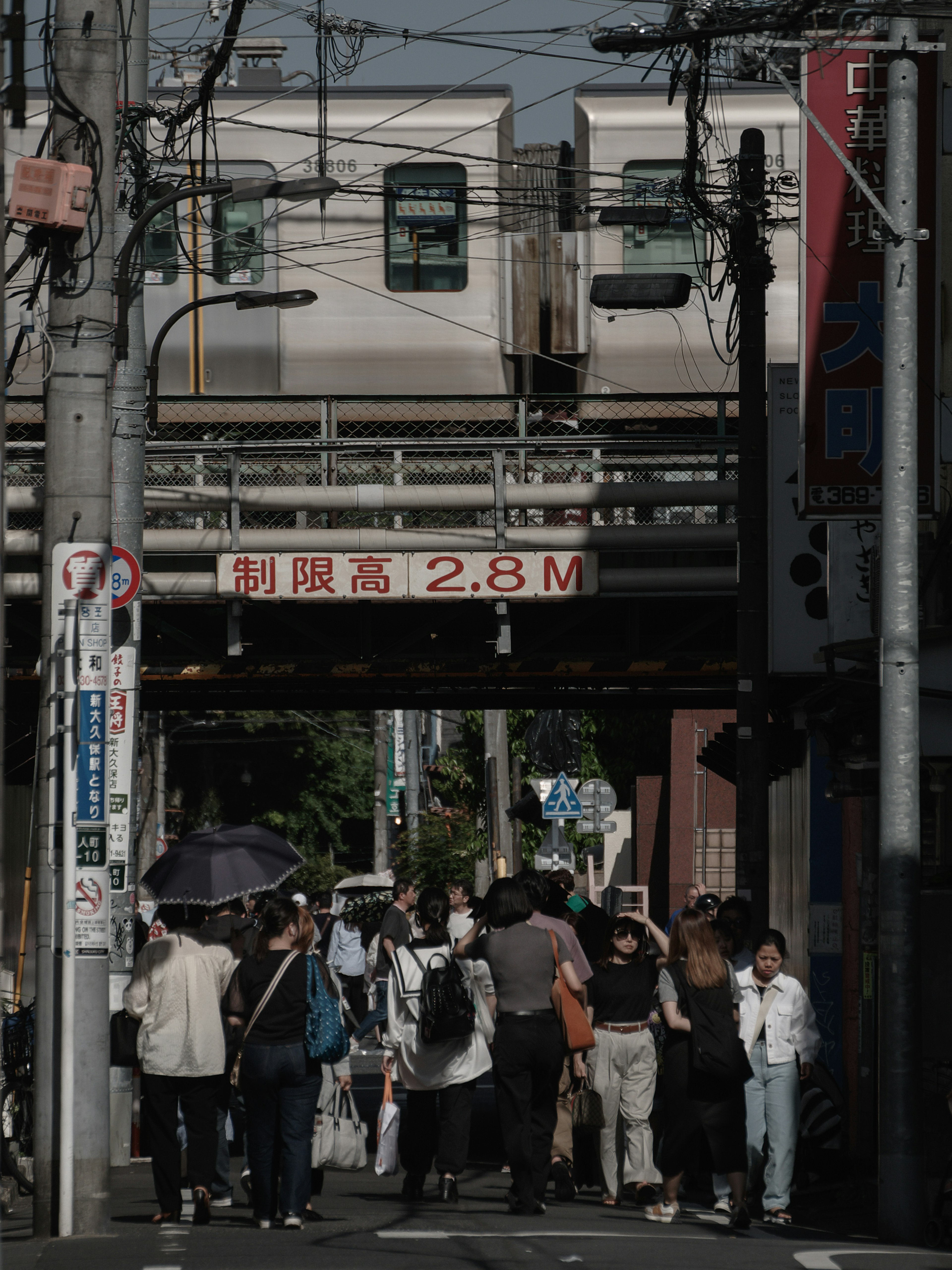 人々が電車の下を通る風景 2.8メートルの高さ制限の標識