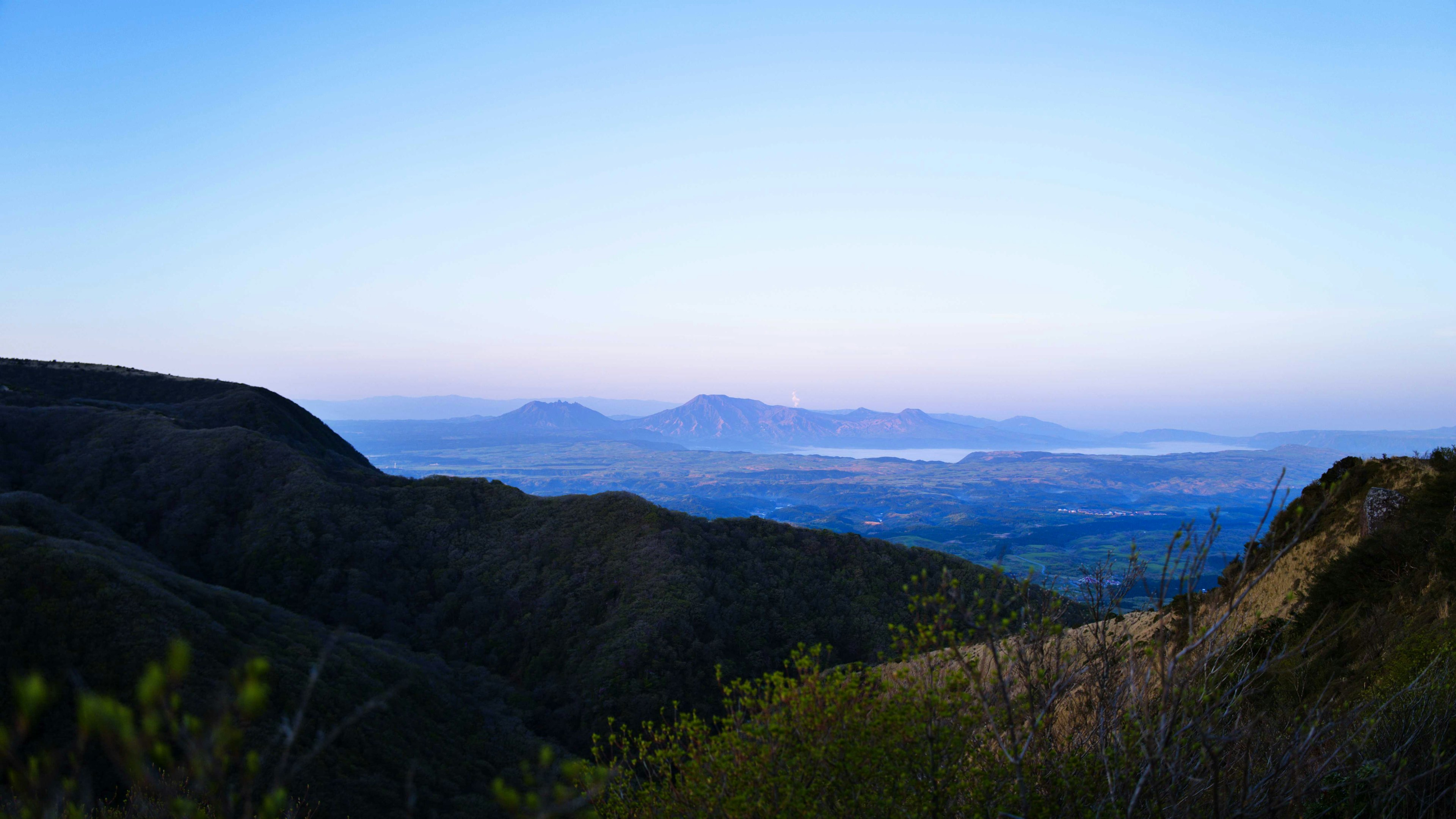 Vista escénica de montañas bajo un cielo azul con suave luz de la tarde