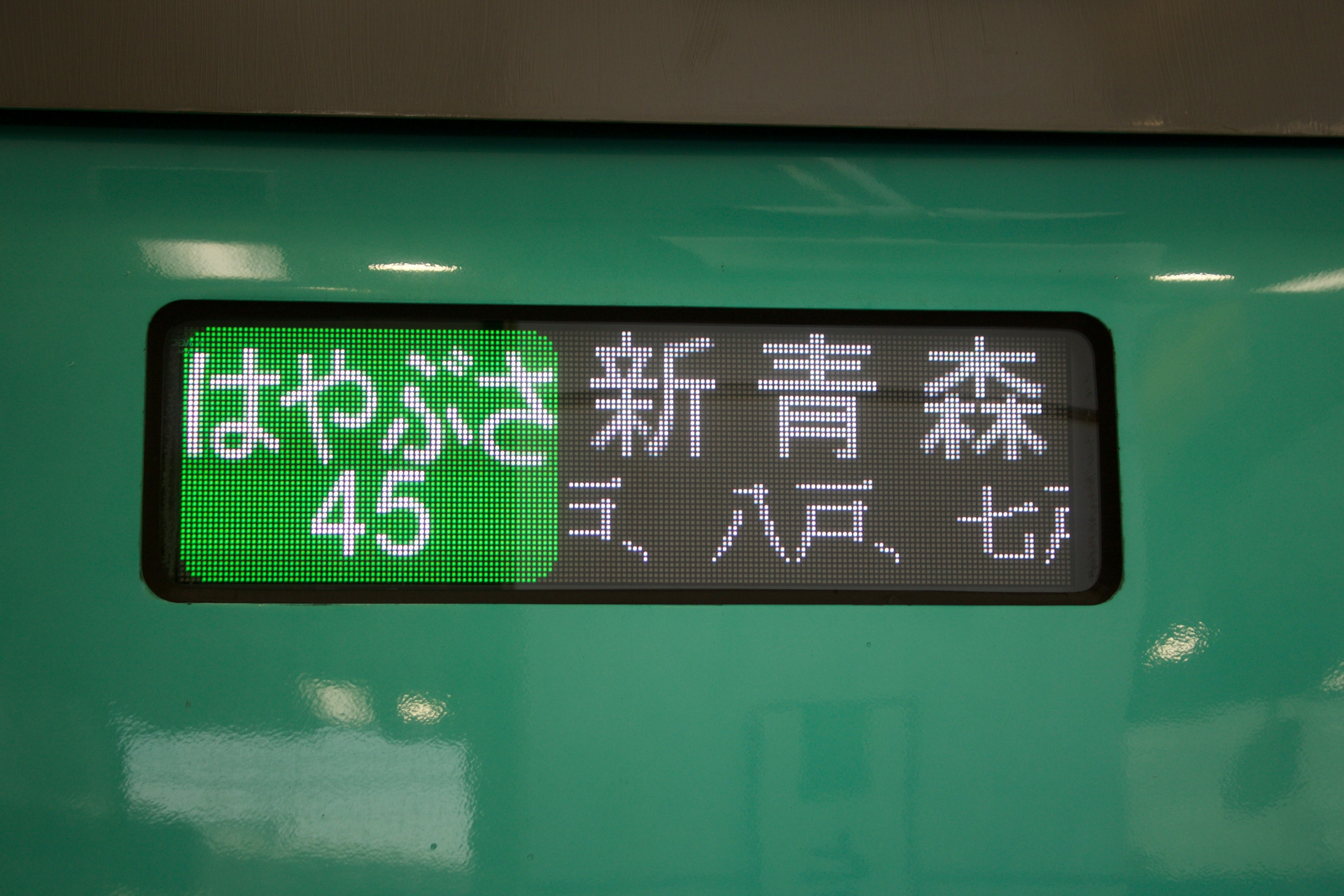 Papan tujuan kereta hijau menampilkan Shin-Aomori