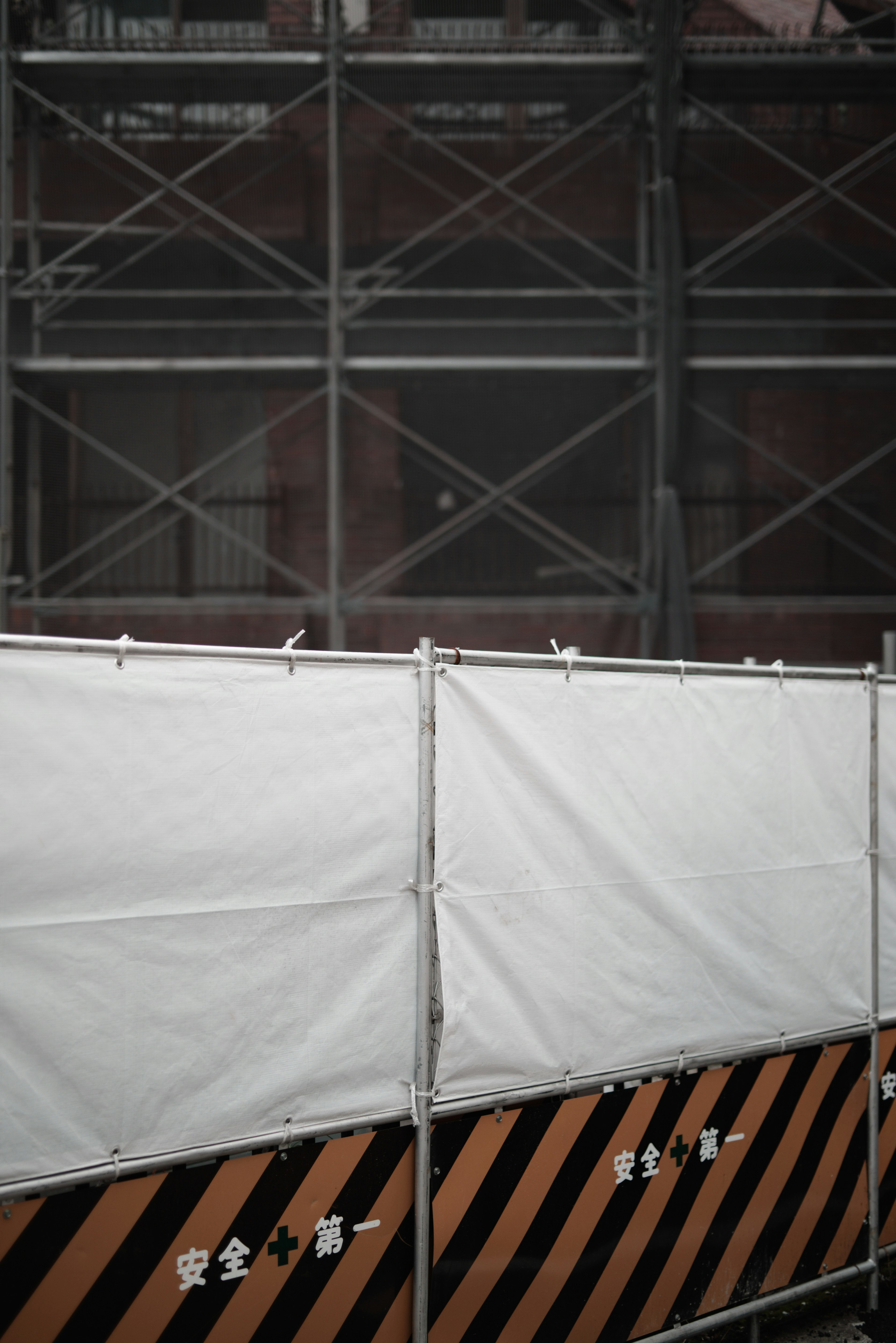 Construction site with white tarp and black and orange striped barricade