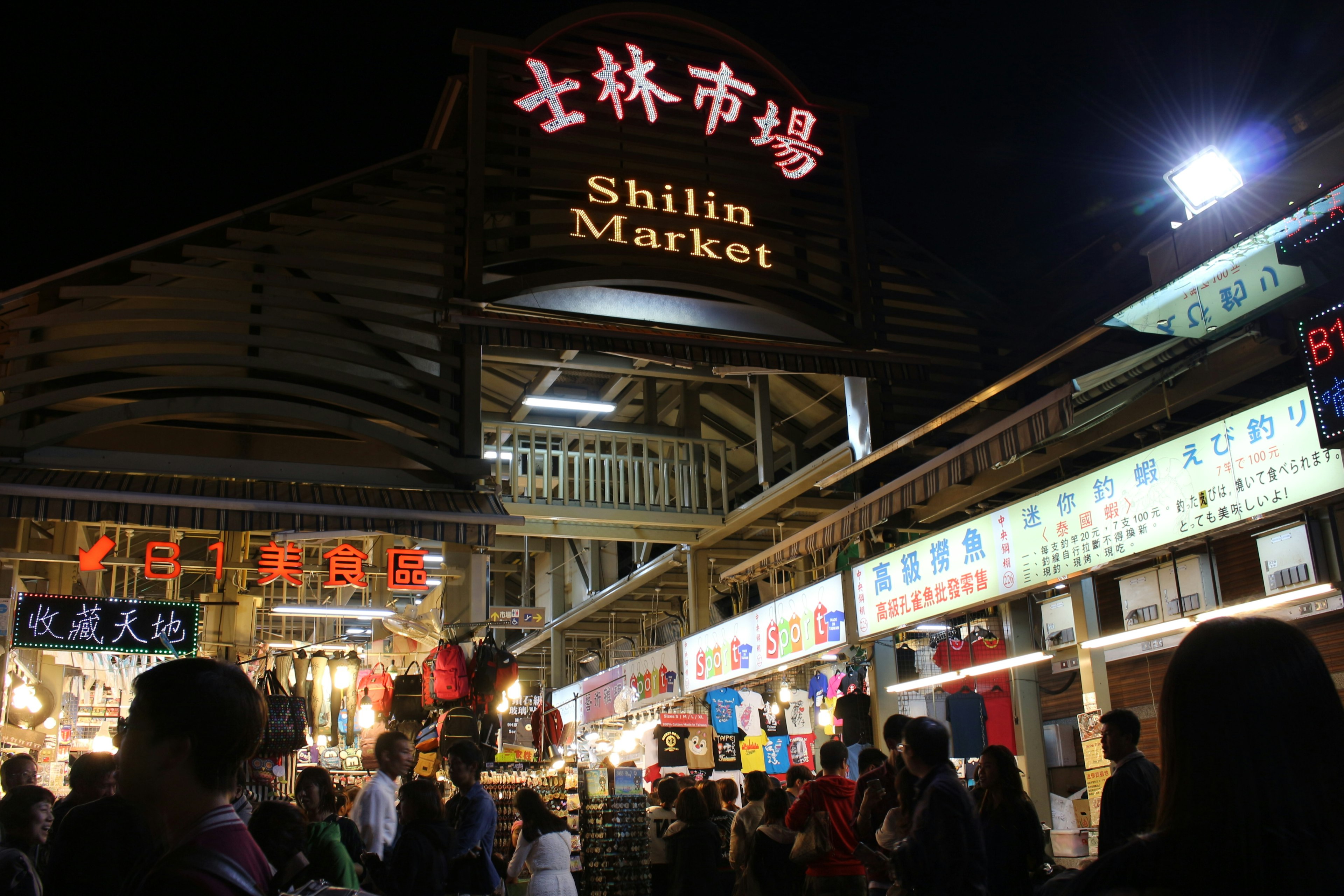 Escena nocturna del mercado de Shilin con puestos vibrantes y letreros brillantes