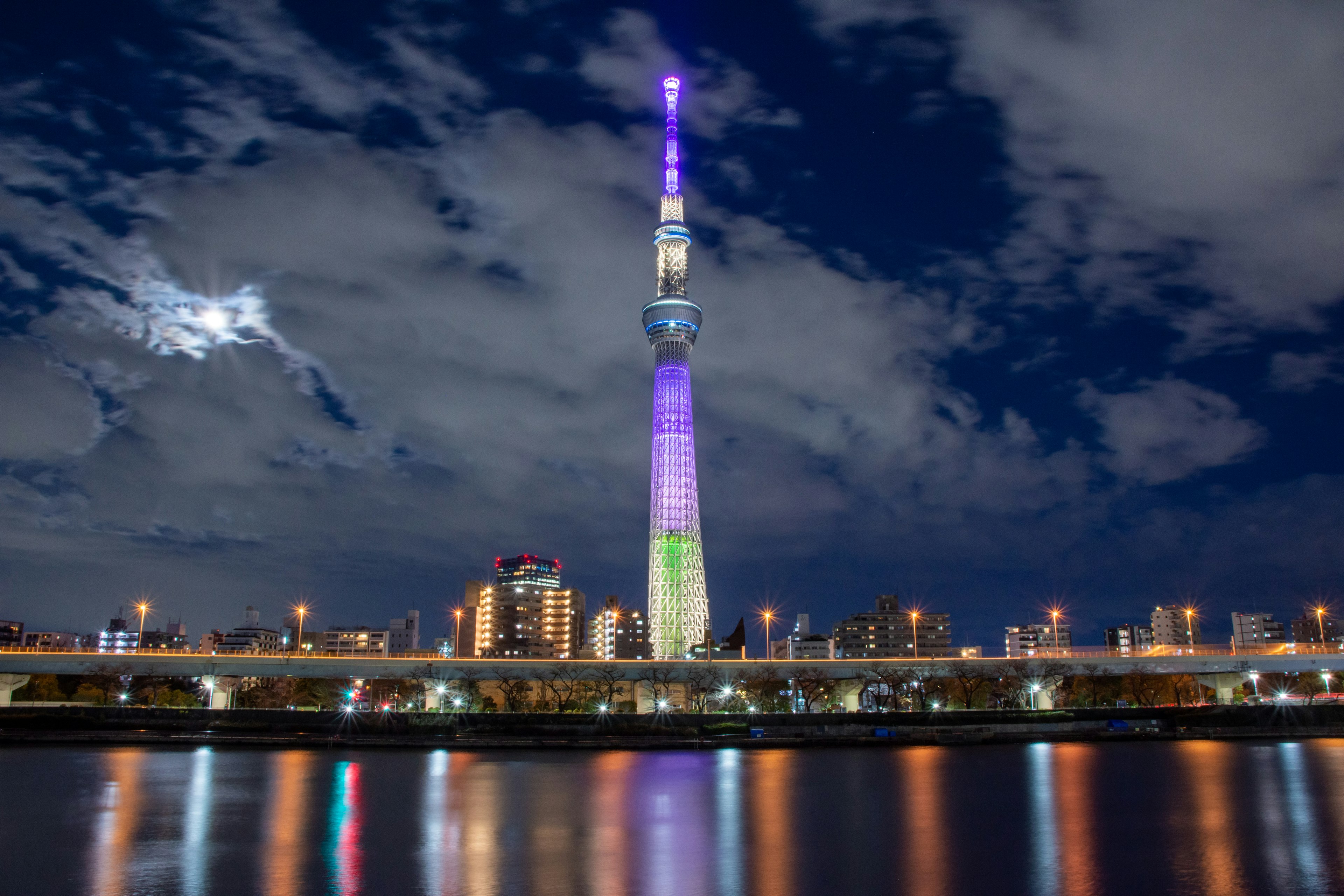 东京晴空塔夜间照明，色彩斑斓的灯光在水面上反射