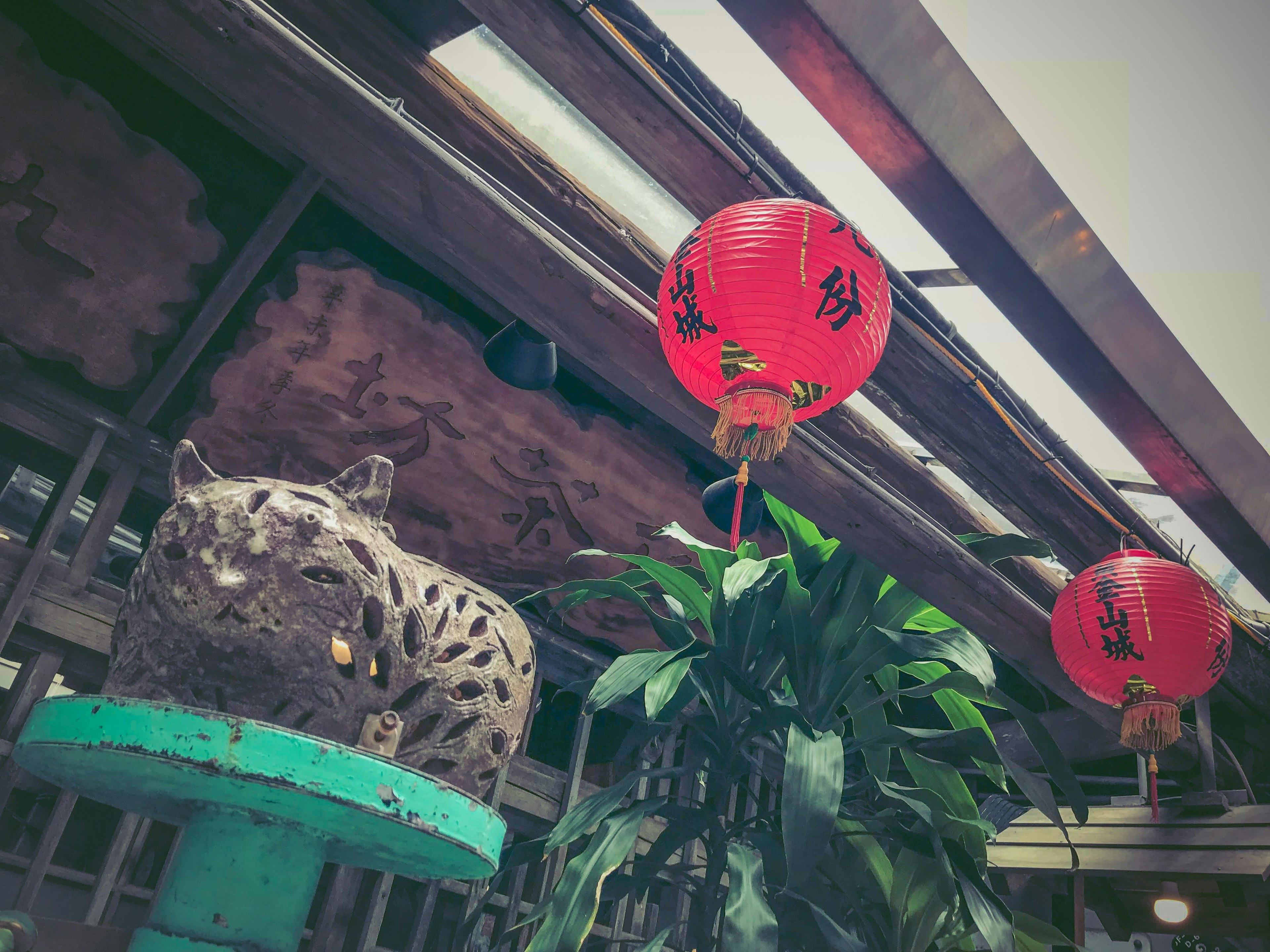 Cat sculpture with red lanterns and greenery