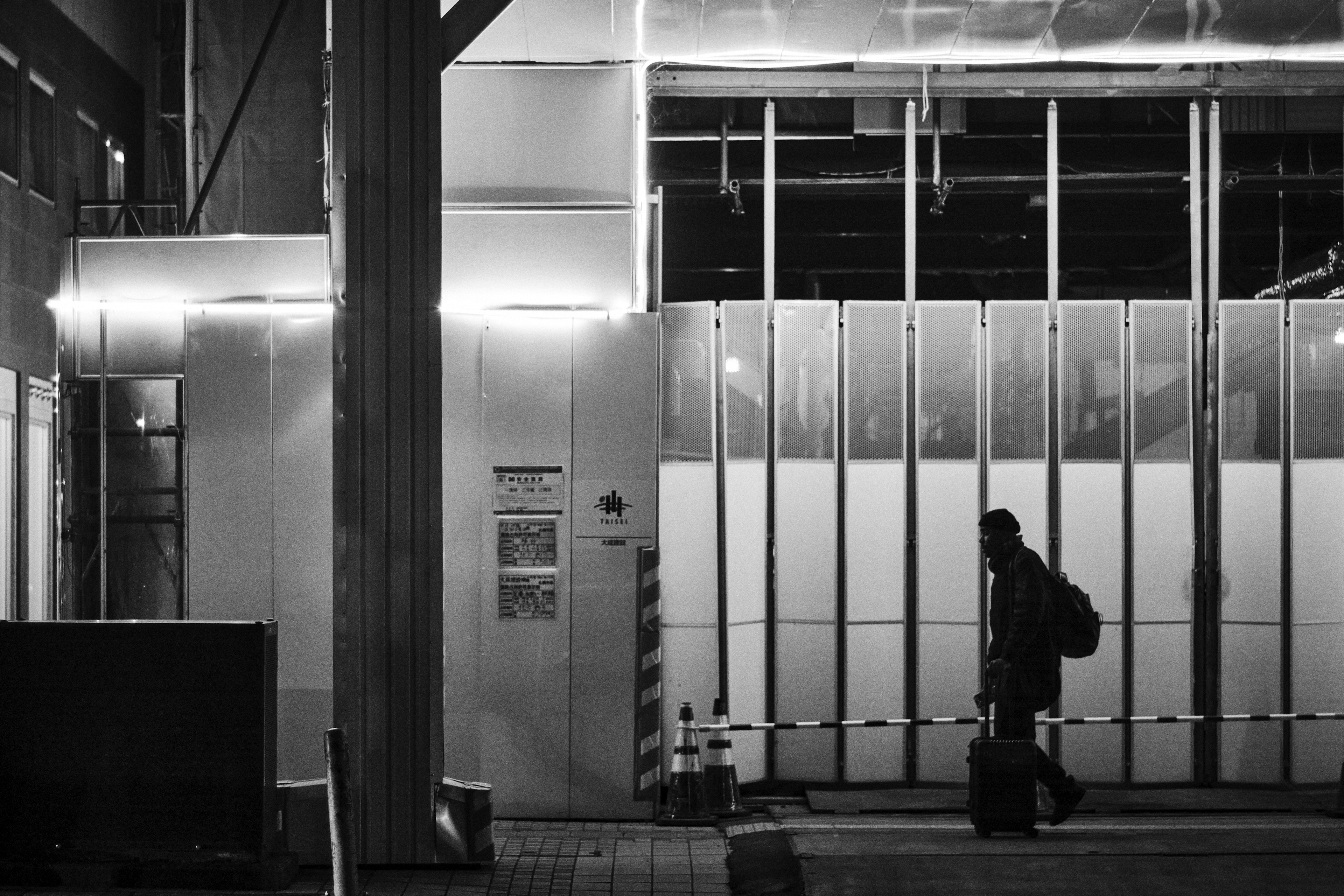 A person walking at night beside a brightly lit building