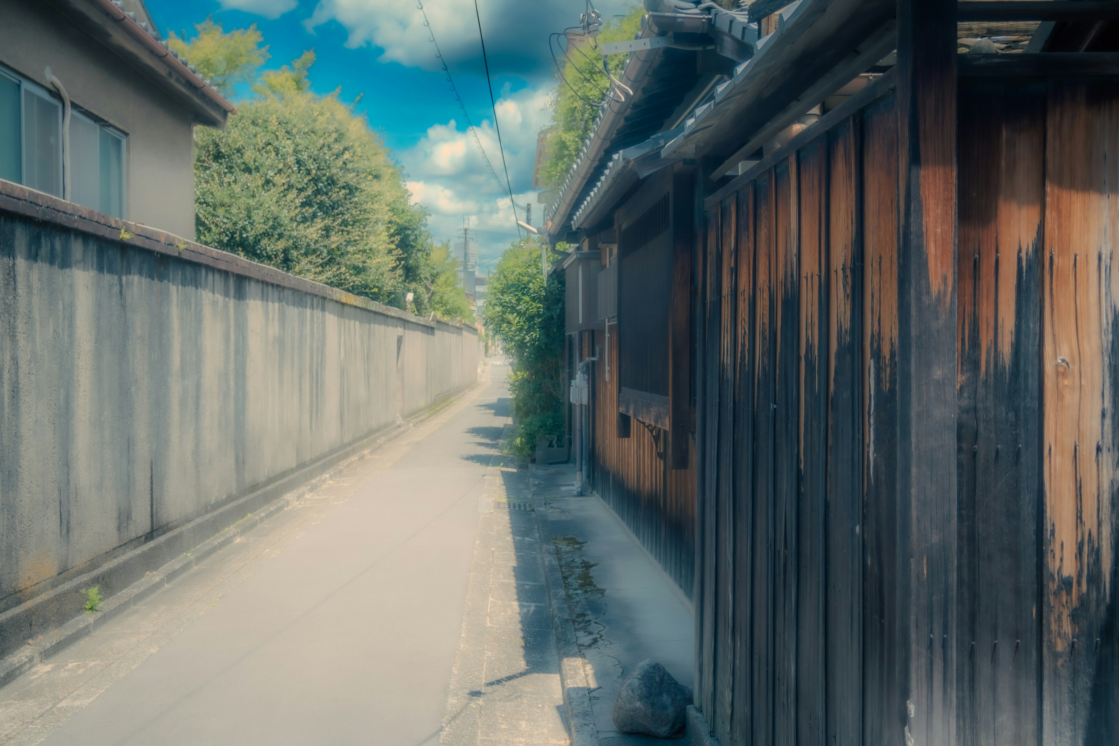 Narrow pathway lined with traditional wooden fences and blue sky