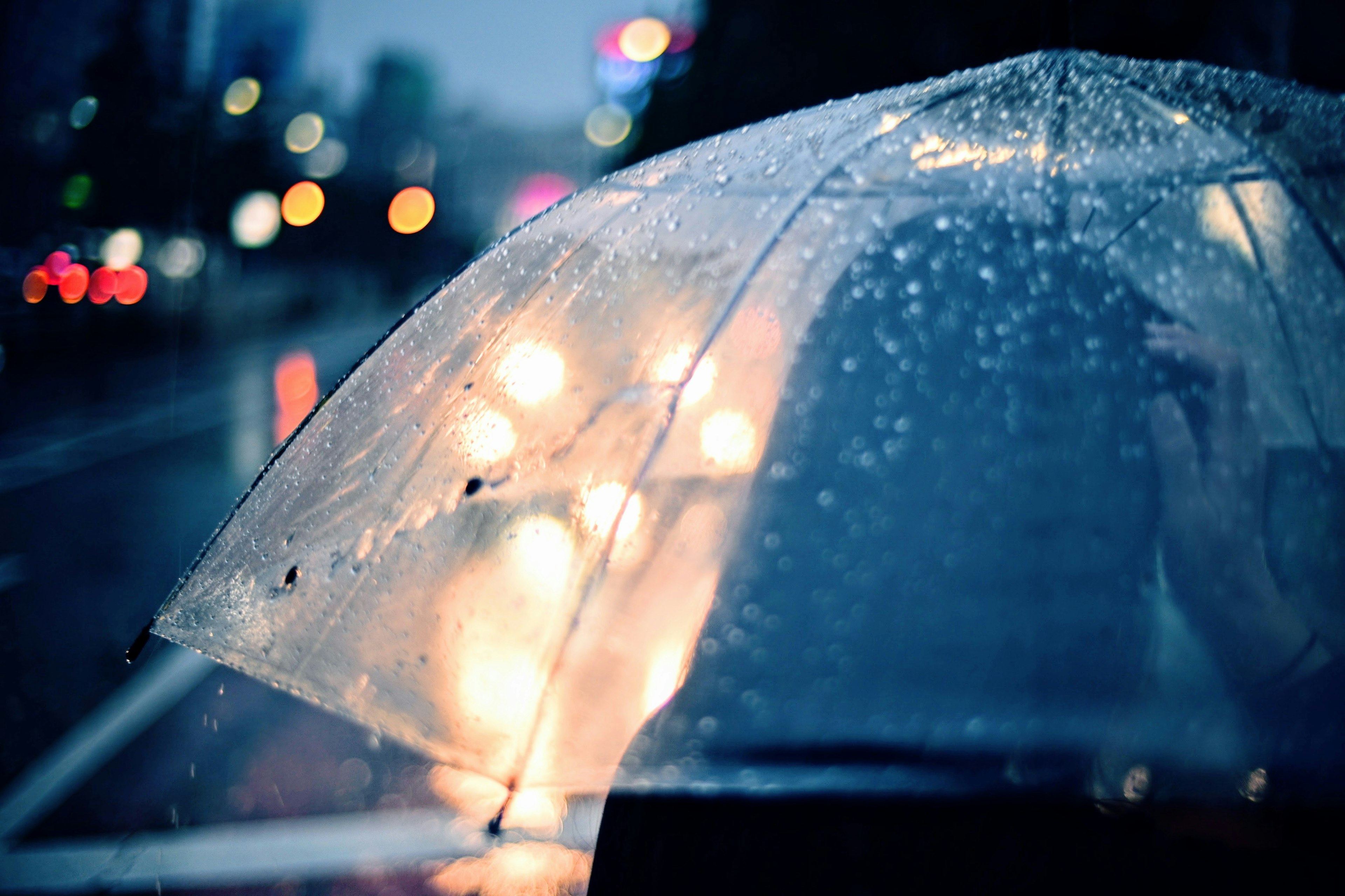 Transparent umbrella in the rain with blurred city lights