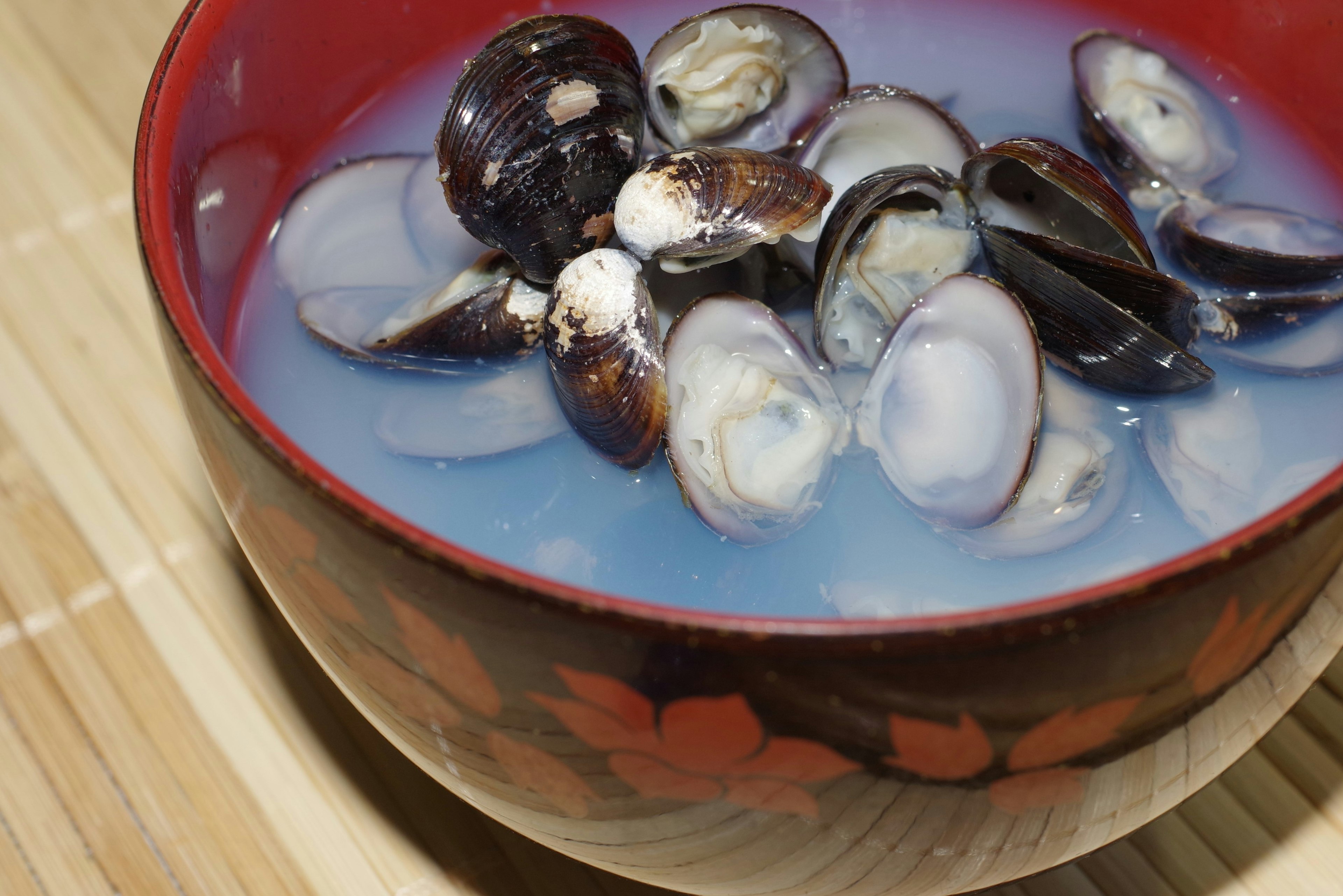 Clam soup in a red bowl with blue liquid