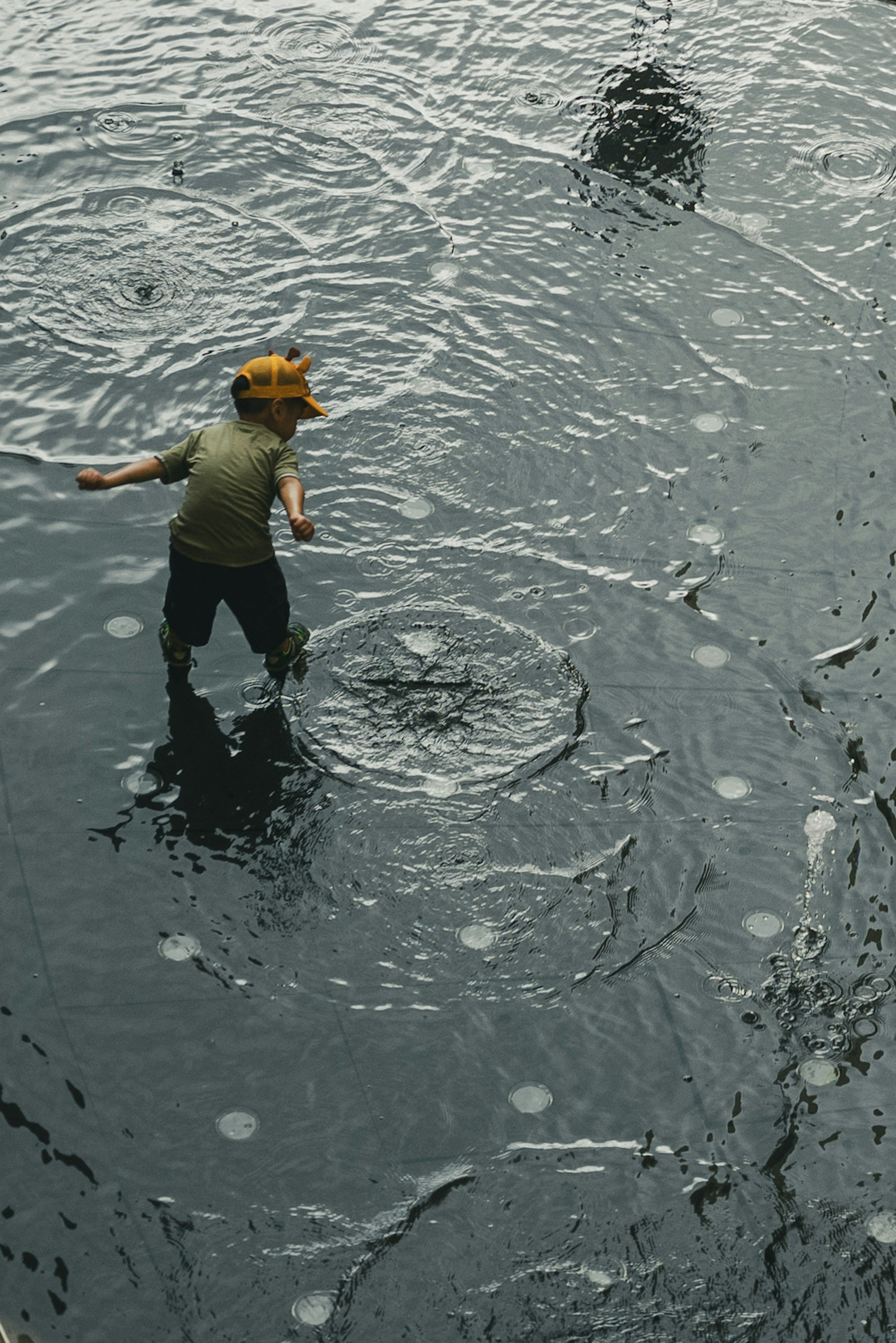 A child playing in the rain splashing in puddles