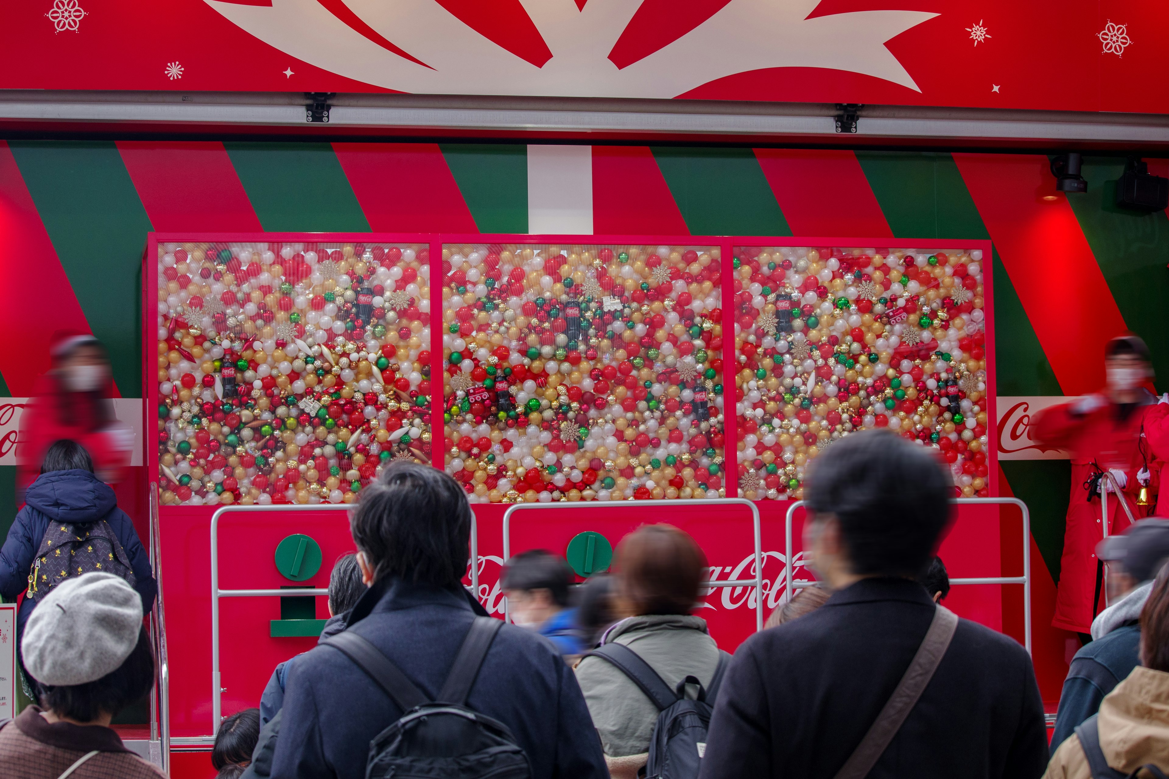 People gathered in front of a festive Christmas display with colorful decorations