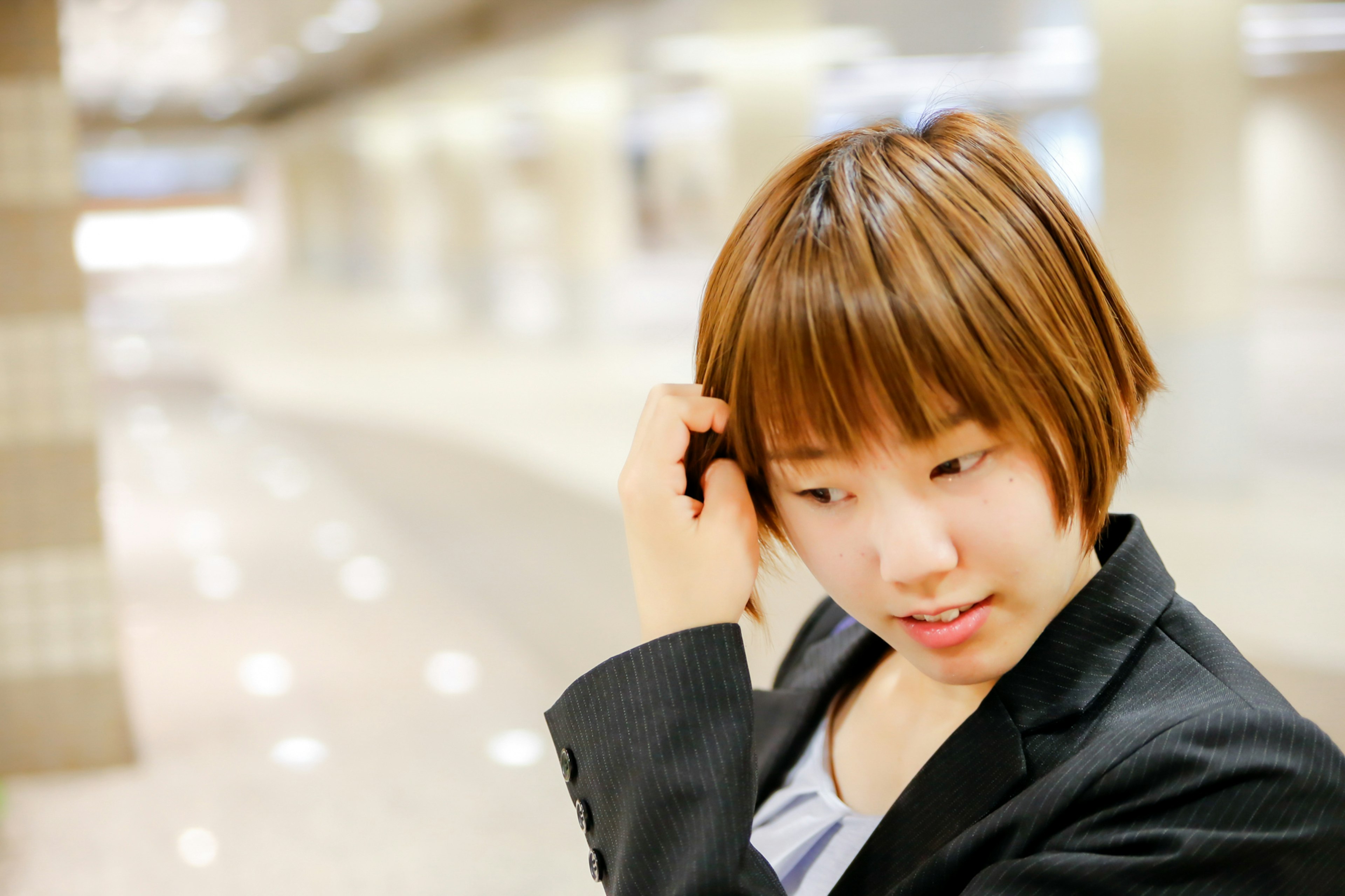 Mujer joven con traje de negocios en interiores tocándose el cabello