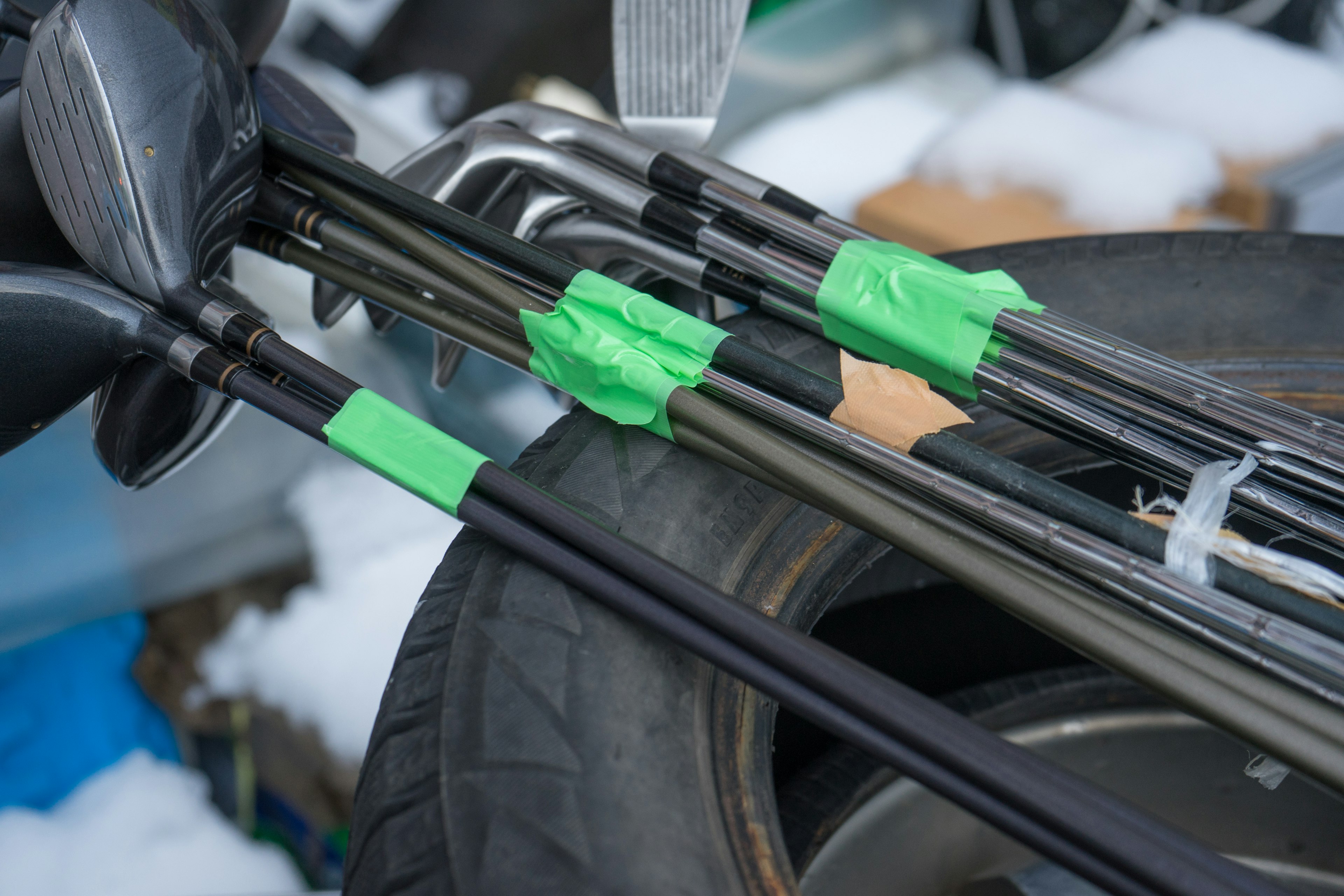 Golf clubs secured to a tire with green tape