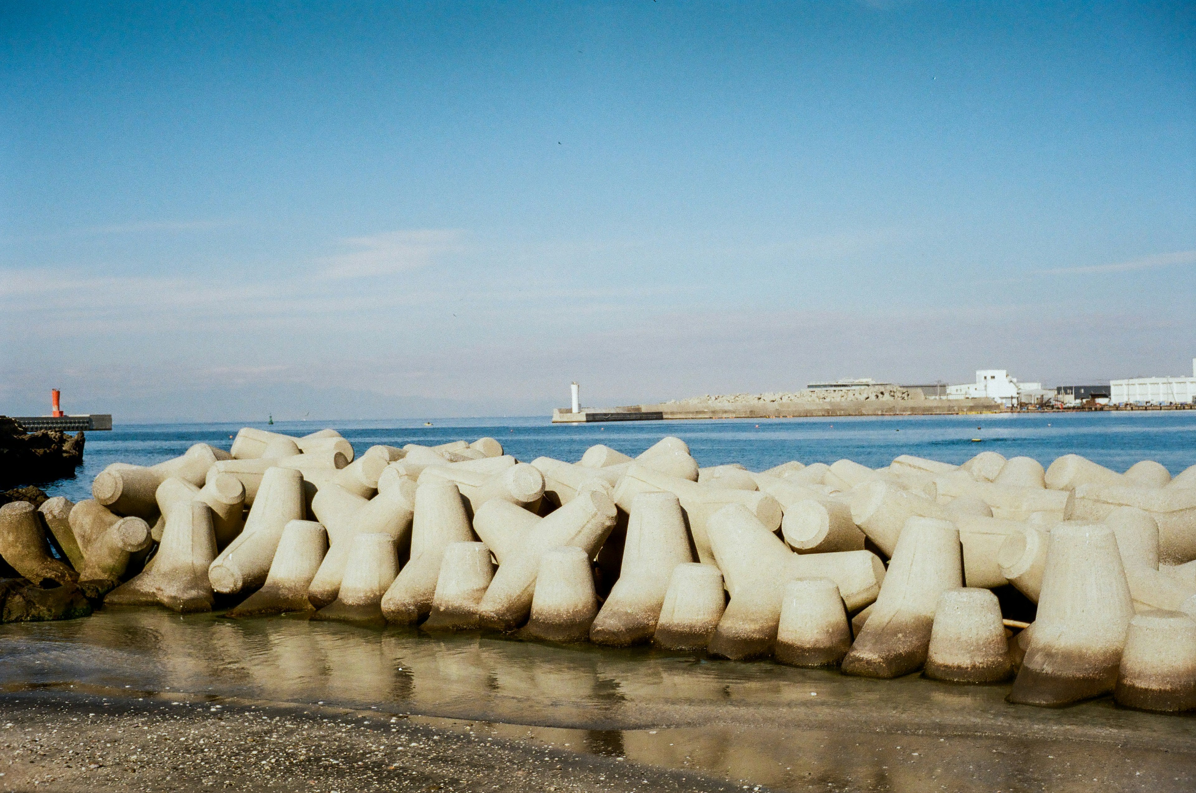 Rompeolas de concreto a lo largo de la costa con cielo azul claro