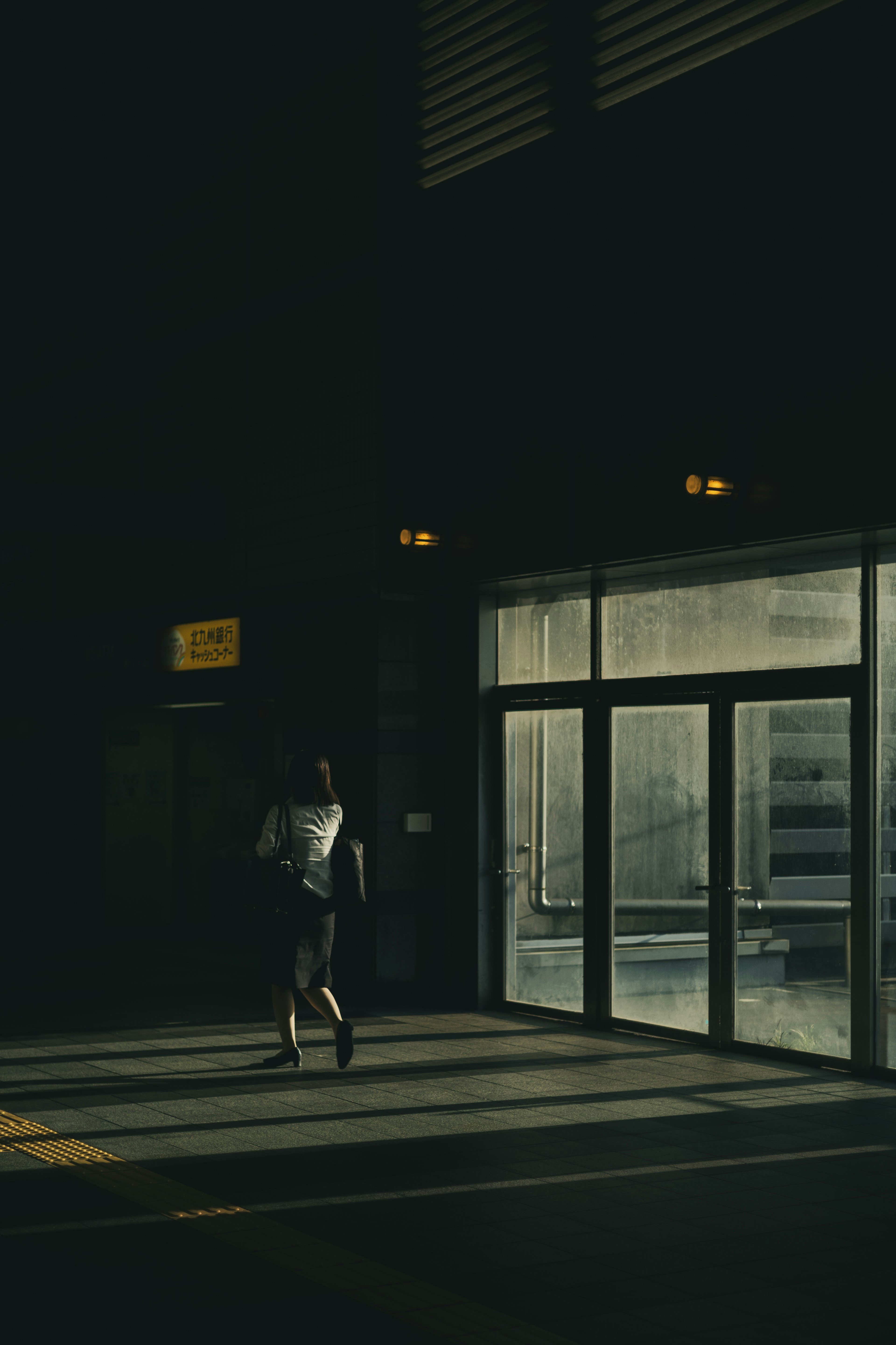 Silhouette of a person walking through a door in a dark background